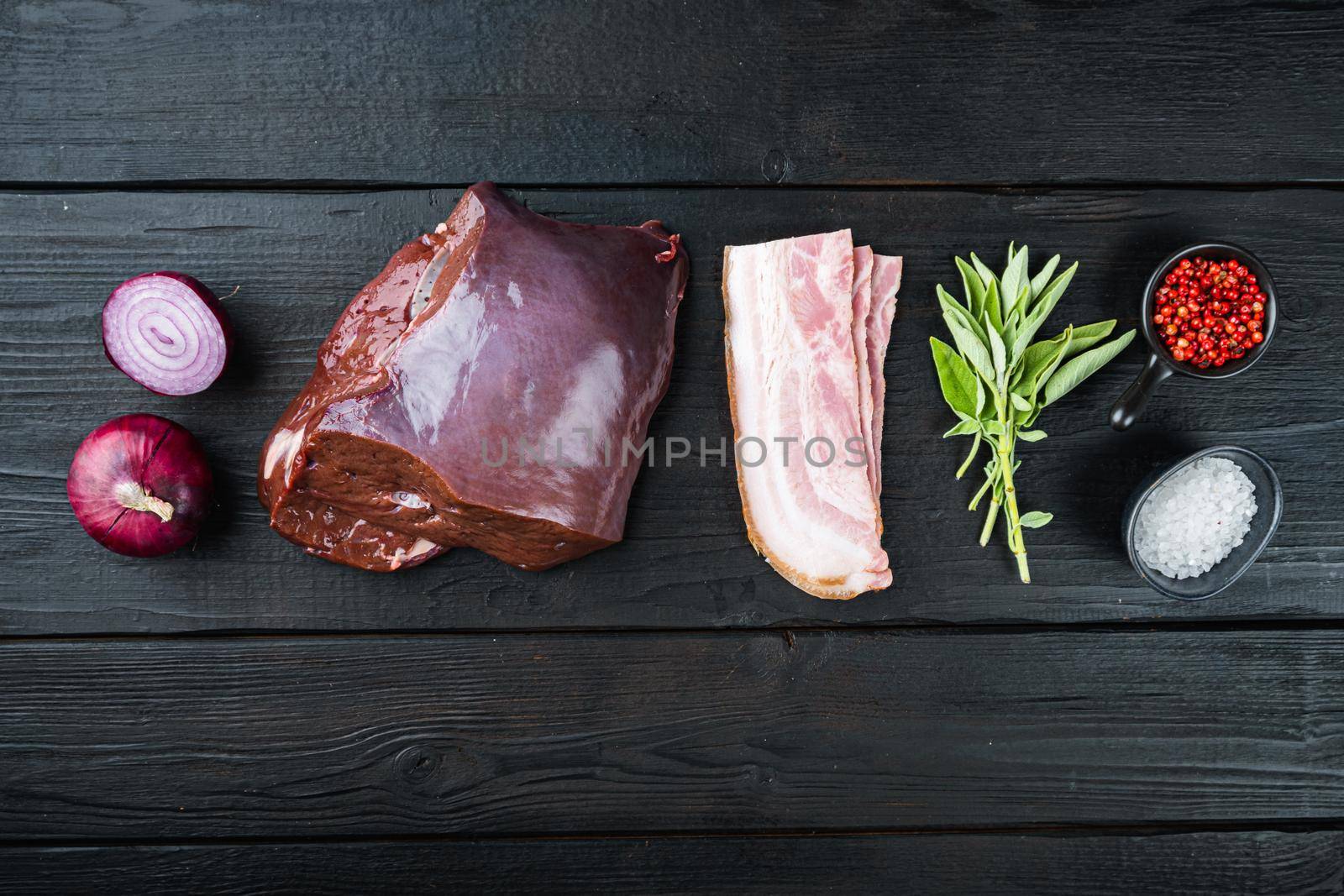 Raw liver with bacon and onion on black wooden background, flat lay.