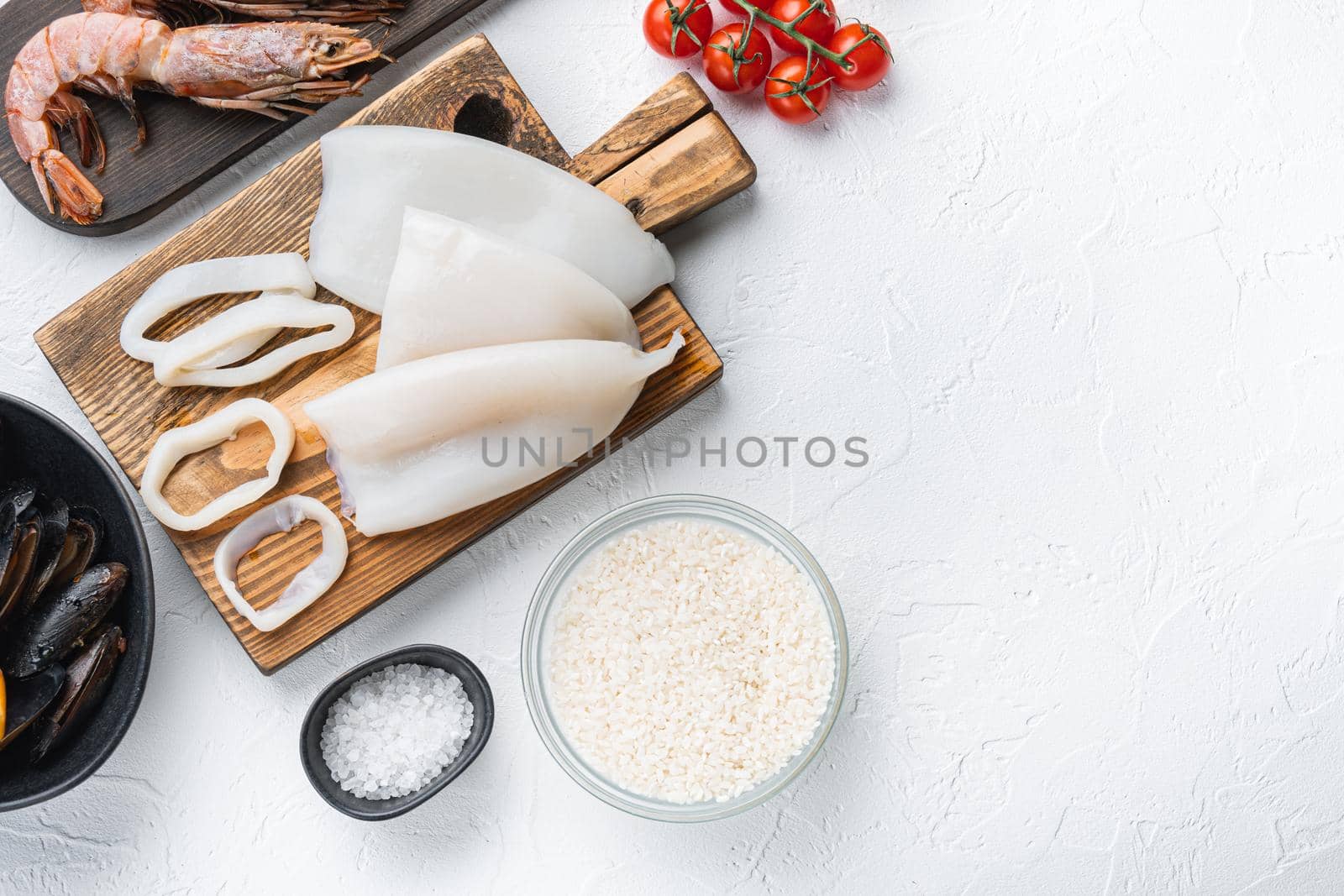 Raw ingredients for paella with seafood on white background, top view with space for text, food photo.