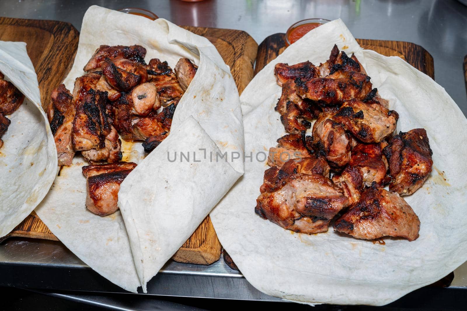 Shish kebab in pita is ready to eat. Lavash with barbecue on a wooden board.