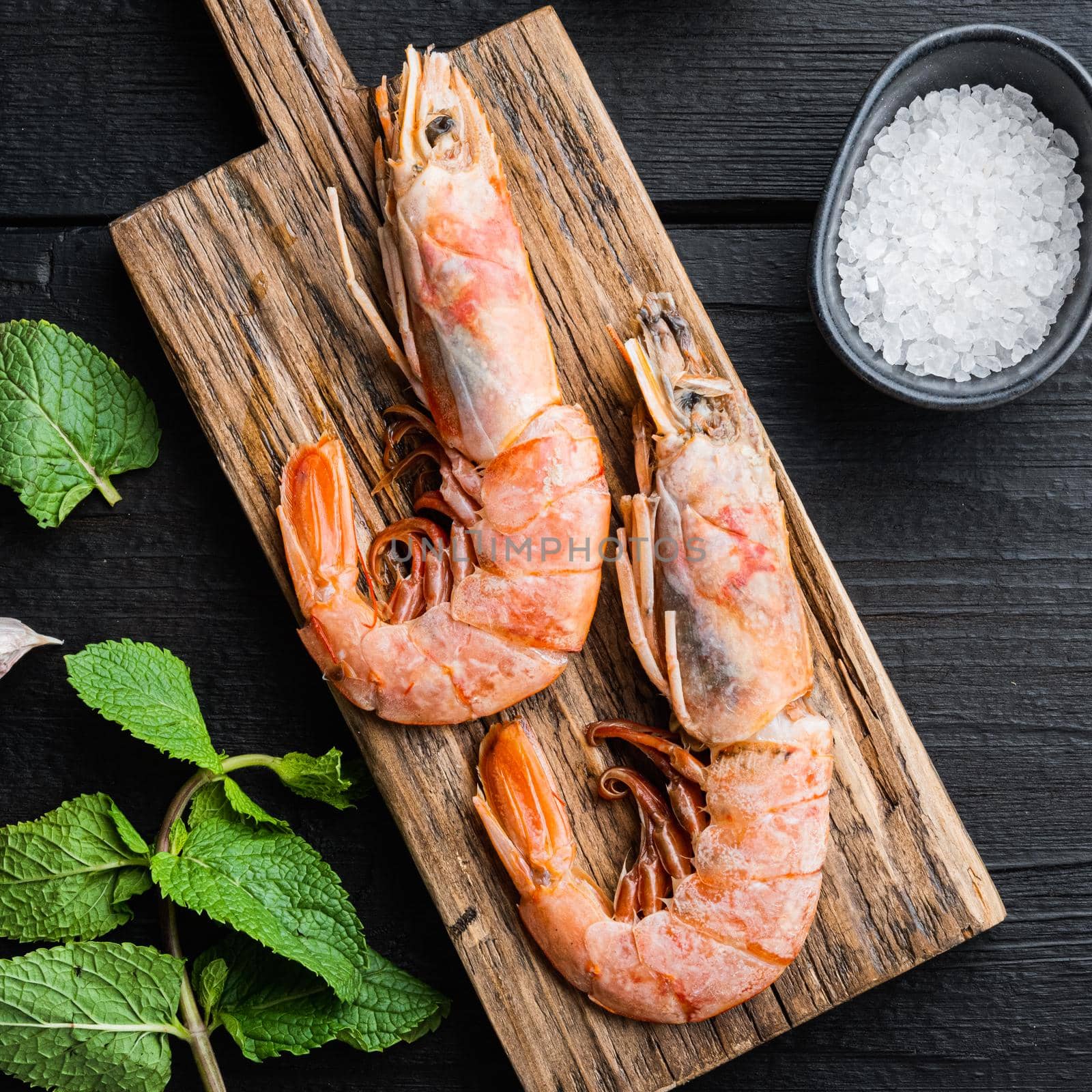 Seafood scampi on wooden board on black wooden background, flat lay, food photo.