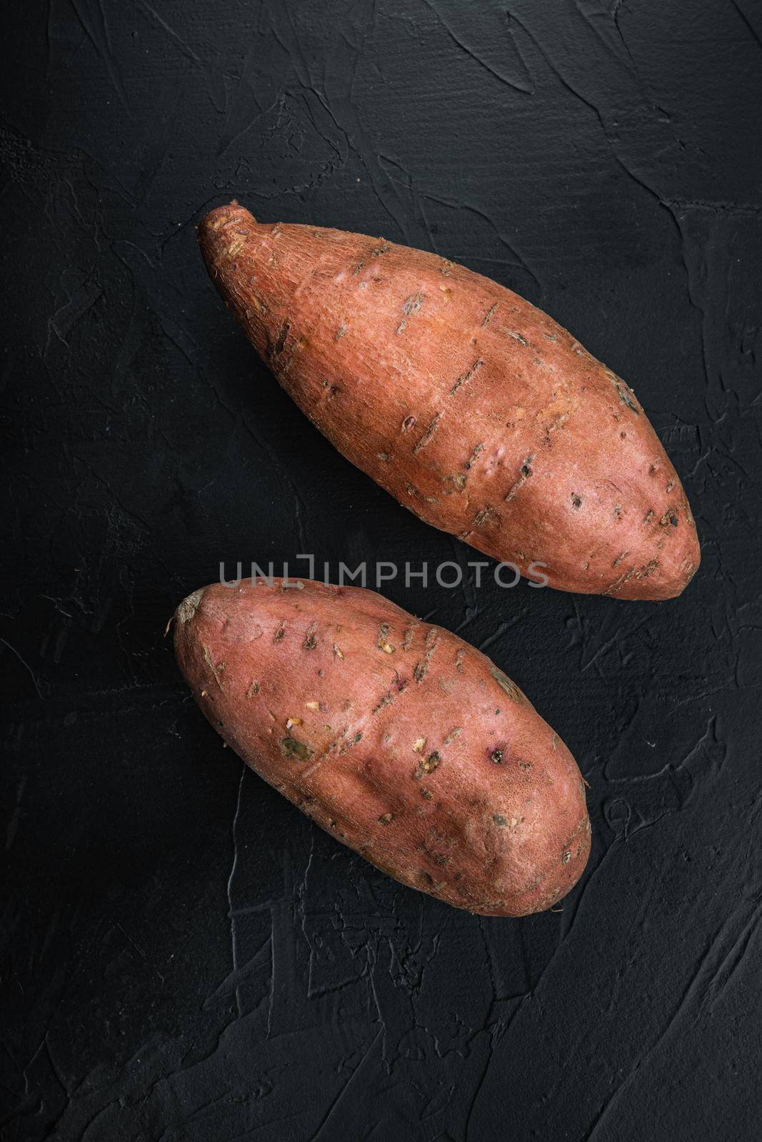 Sweet potato or batat on black background, top view.