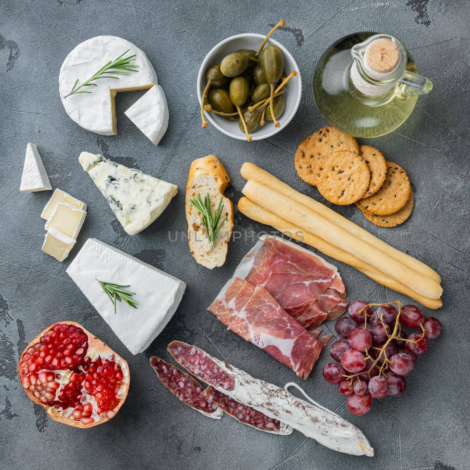 Antipasti platter with fresh cheese, bread and olive, on gray background, top view