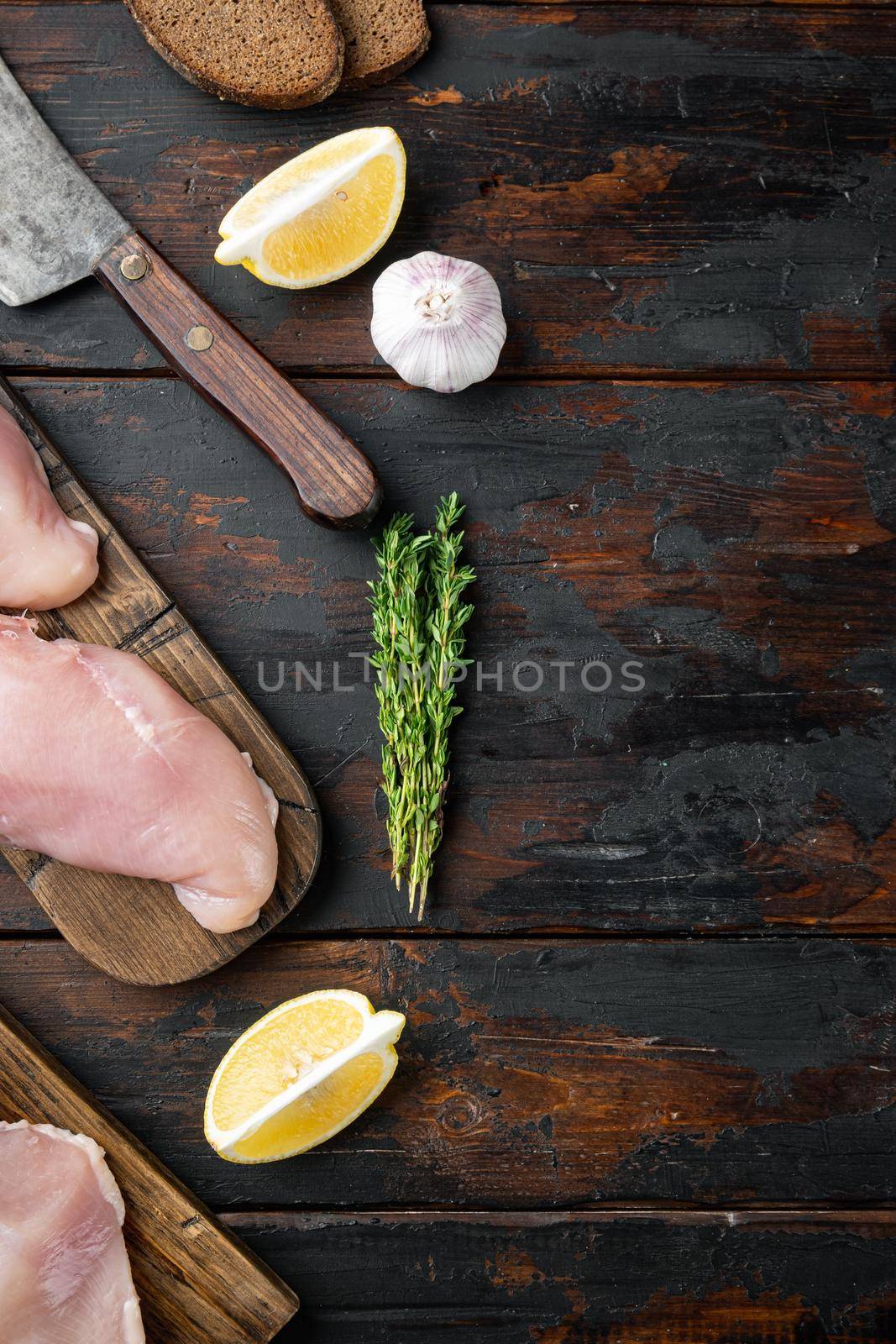 Crumbed uncooked chicken breast ingredient on dark wooden background, flat lay with space for text by Ilianesolenyi