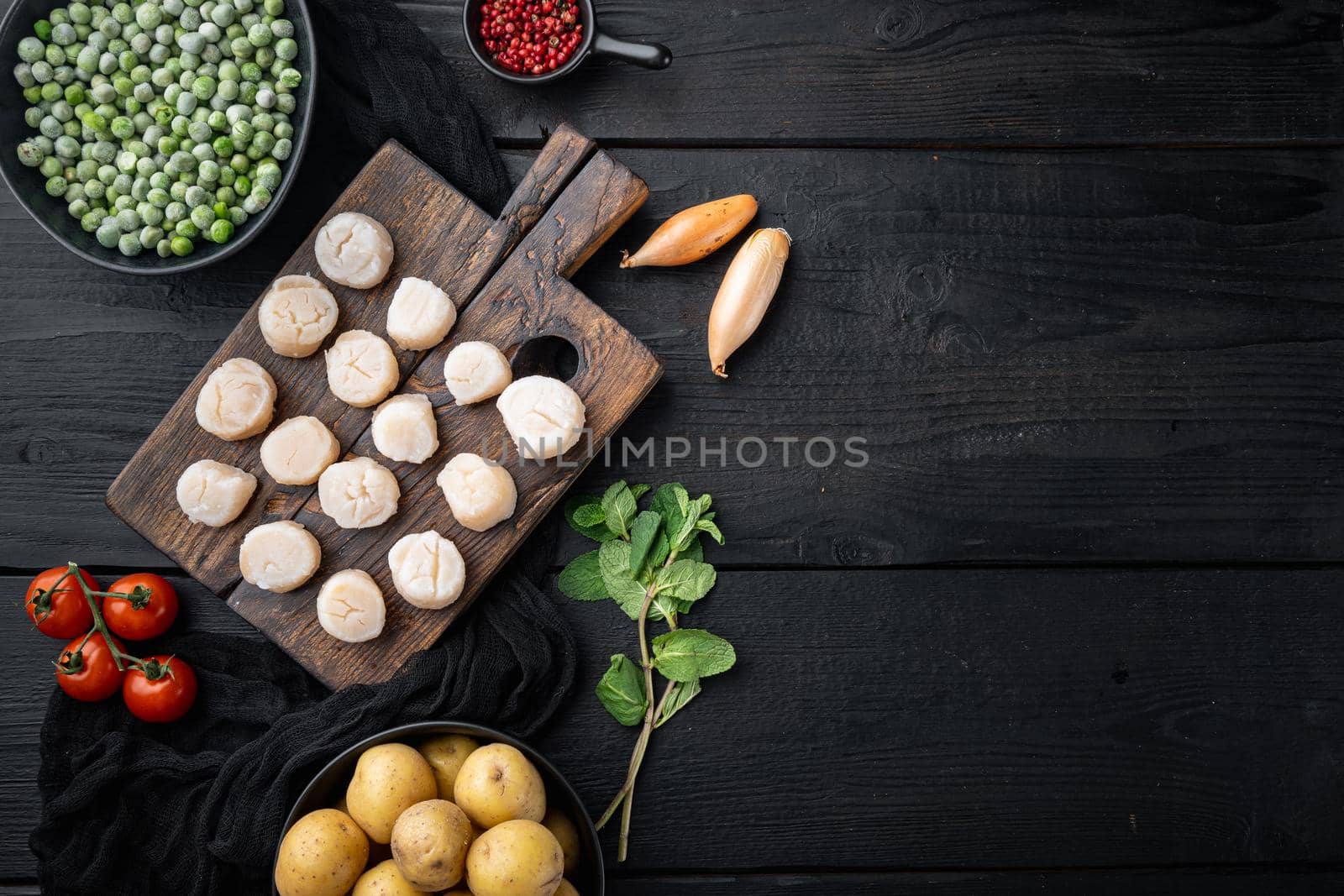 Sea delicacies, scallops with potato, green pea and mint, top view, on black wooden background with copy space