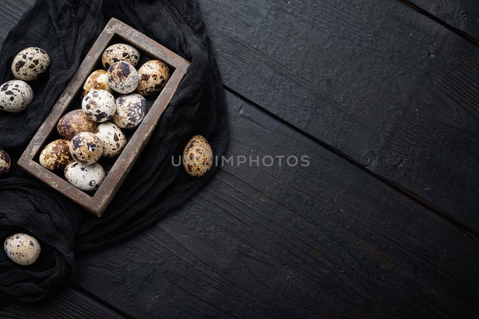 Fresh quails eggs, flat lay, on black wooden background with space for text