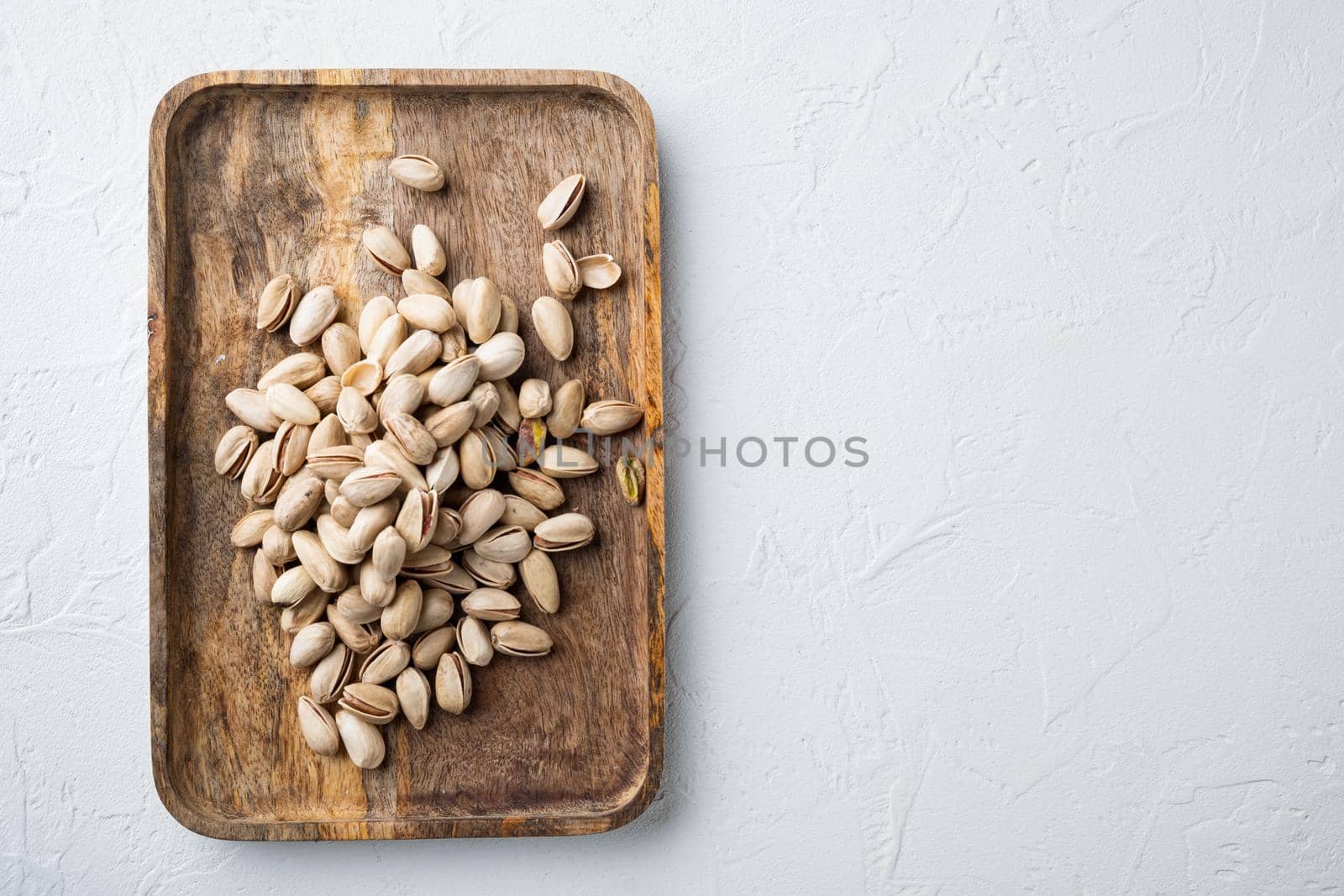 Shelled, unsalted pistachios, on white textured background, top view with space for text