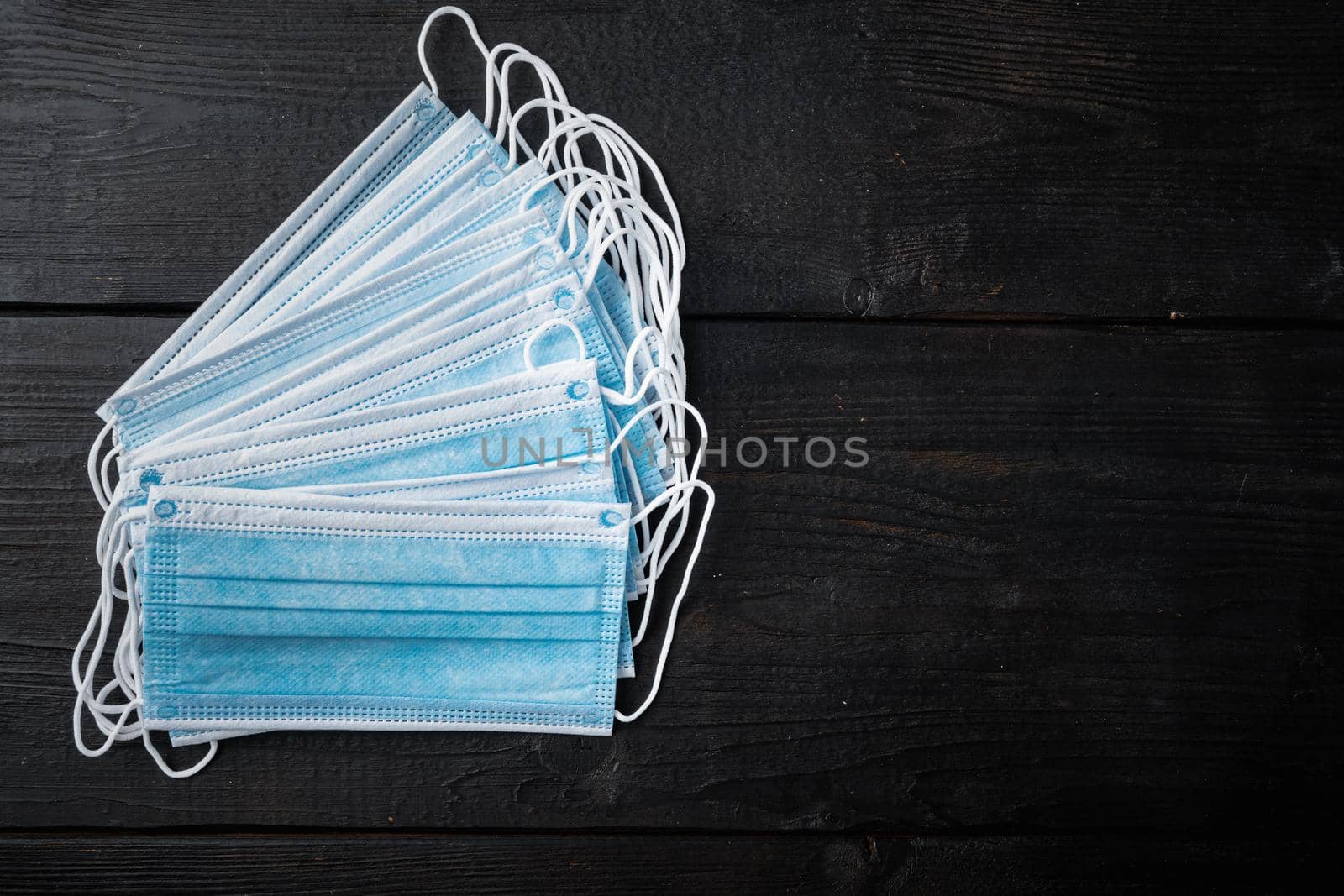 Medical protective disposable mask, surgical mask, coronavirus quarantine, hygiene concept, top view with copy space, on black wooden table