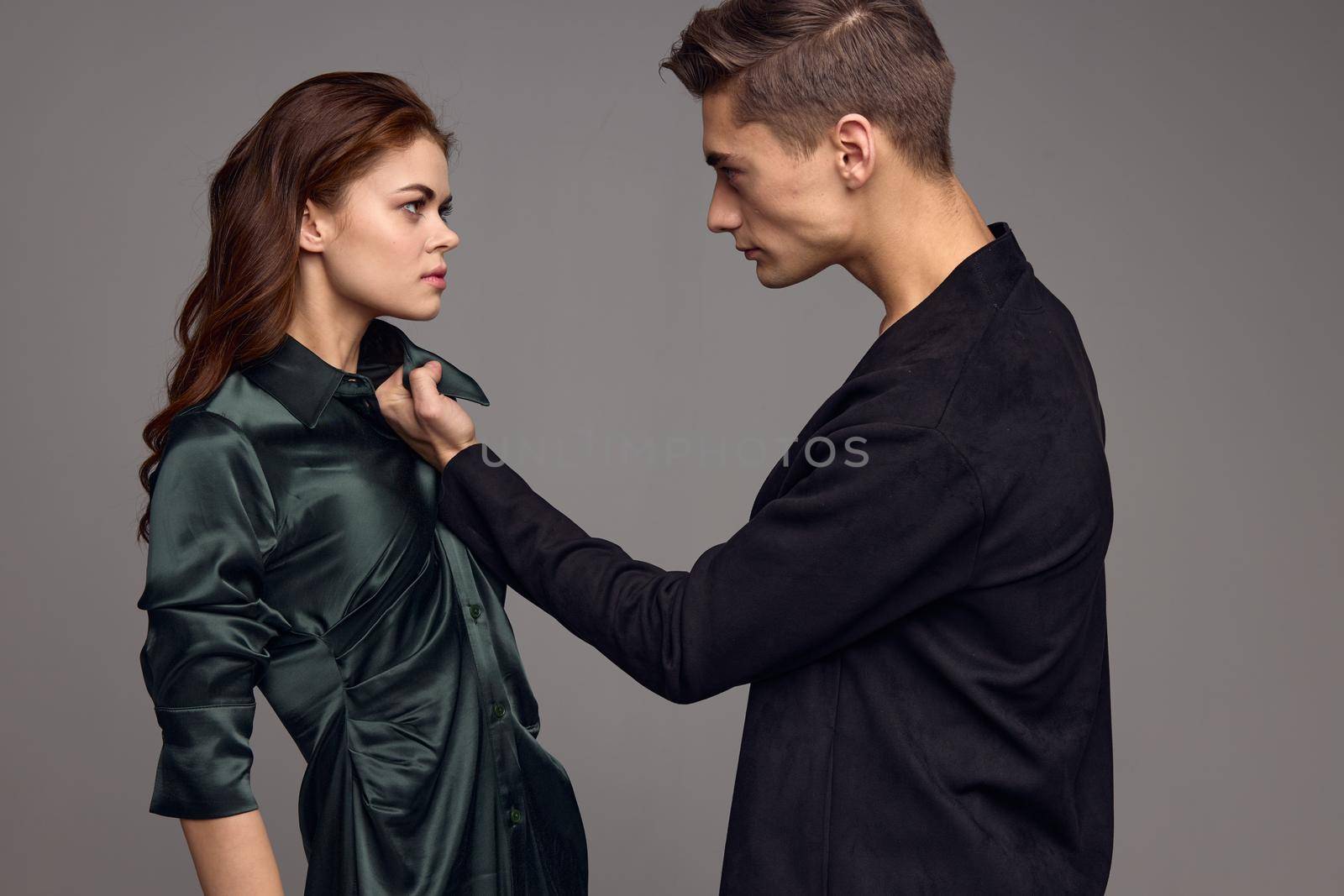 A woman in a silk dress and an aggressive man in a suit on a gray background look at each other. High quality photo