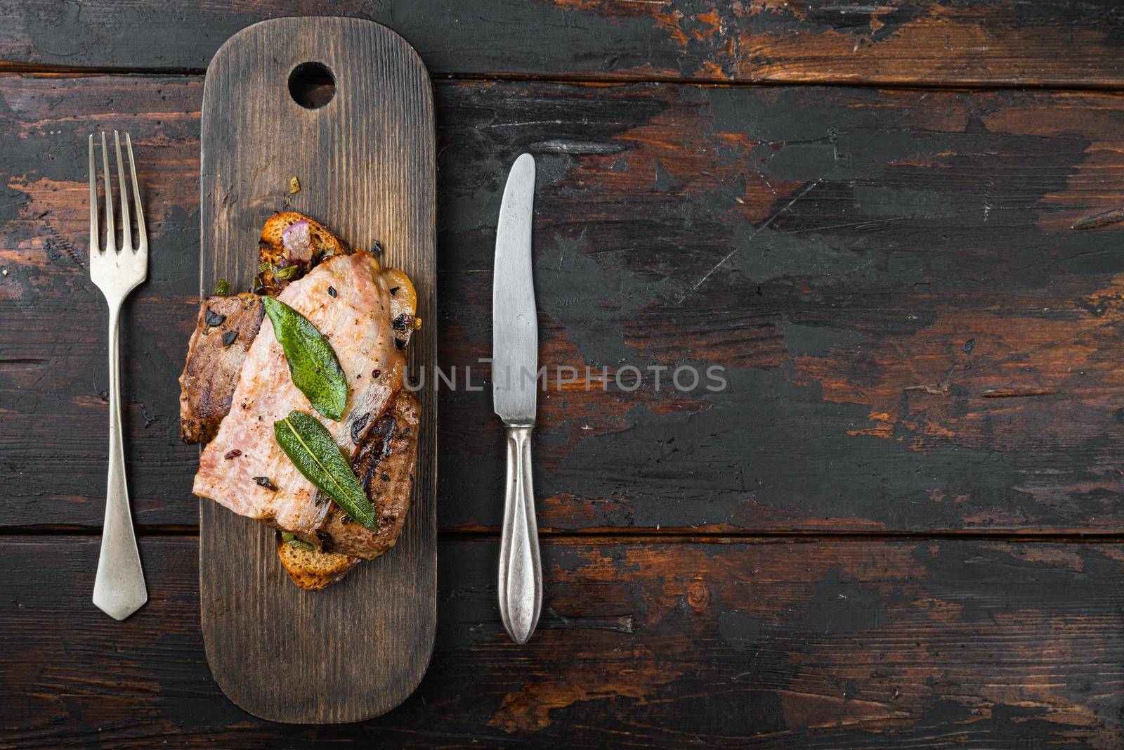 Liver bacon and onions on bread cooked meal served on board, over wooden background, top view with copy space.