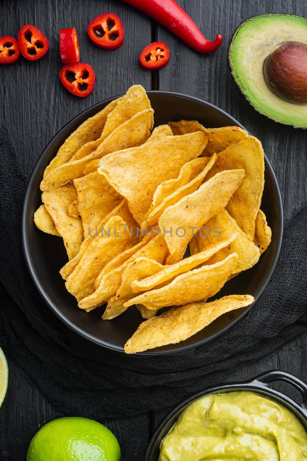 Nachos corn chips with traditional dip sauce set, on black wooden background, top view or flat lay