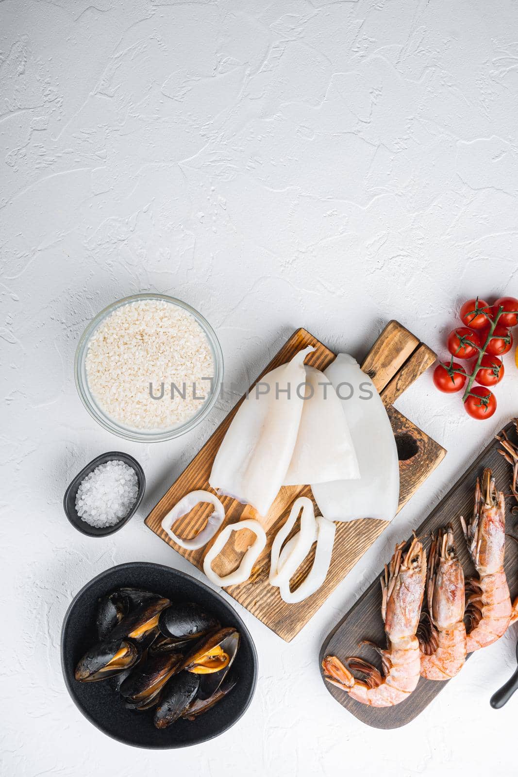 Raw ingredients for paella with seafood on white background, top view with space for text, food photo.