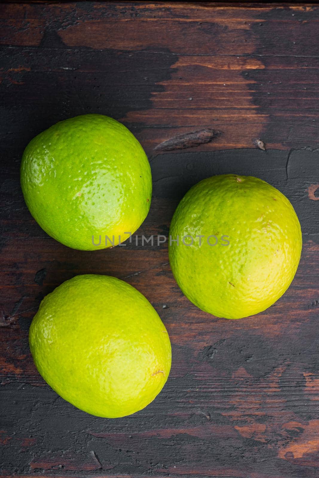 Whole green lime set, on old wooden table, top view or flat lay