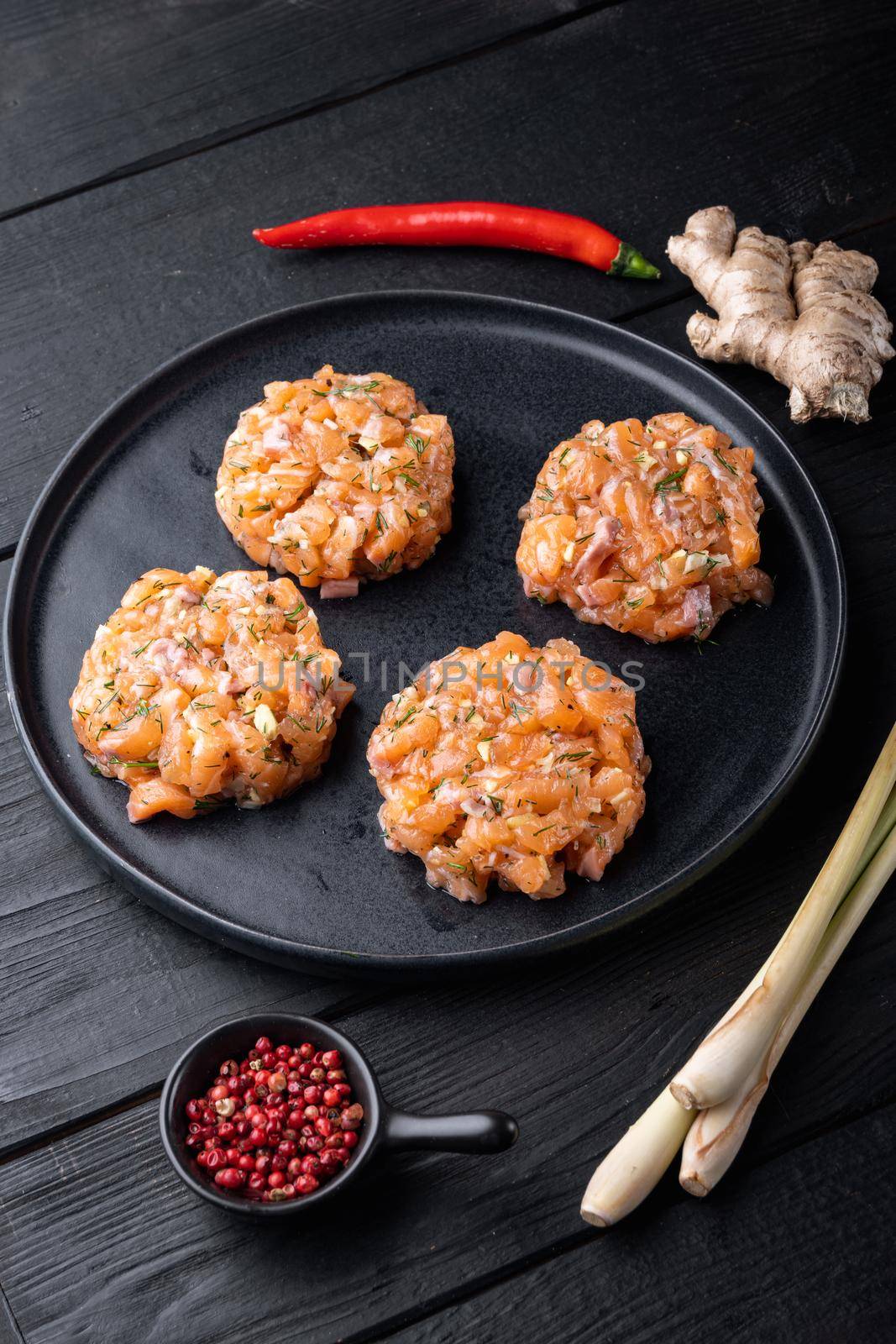 Quick asian raw fish patties with herb, on black wooden table