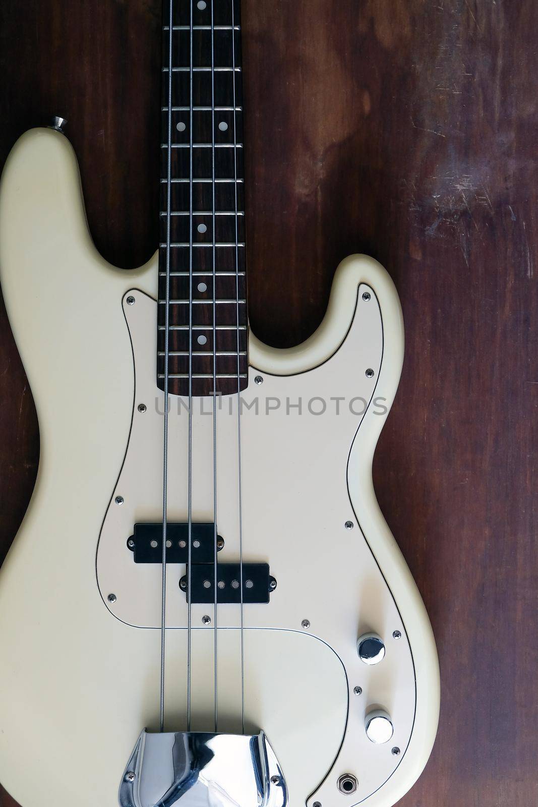 white electric bass guitar on wood background with copy space