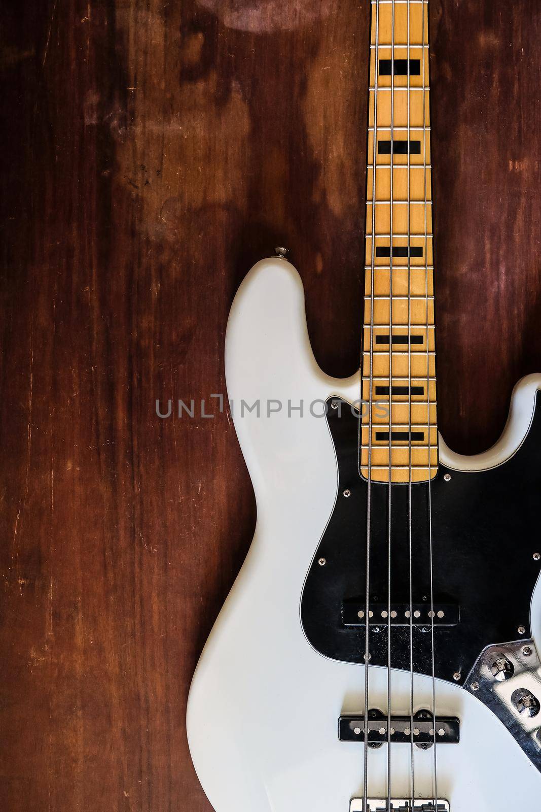 white electric bass guitar on wood background by ponsulak