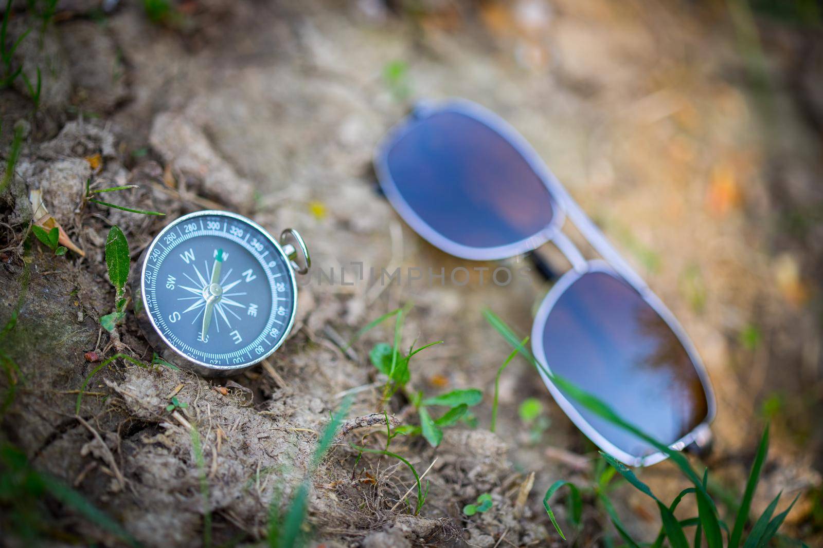 Adventure: Compass and sunglasses are lying on the floor, showing the direction by Daxenbichler
