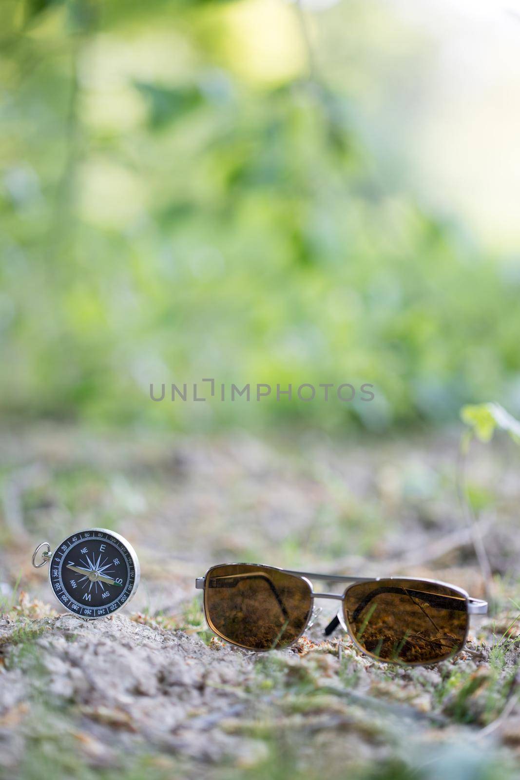 Vintage compass and sunglasses lying on the floor. Adventure and discovery concept.