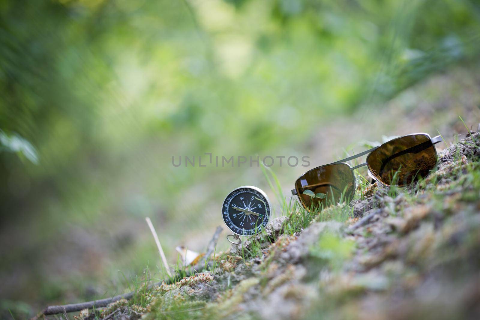 Vintage compass and sunglasses lying on the floor. Adventure and discovery concept.