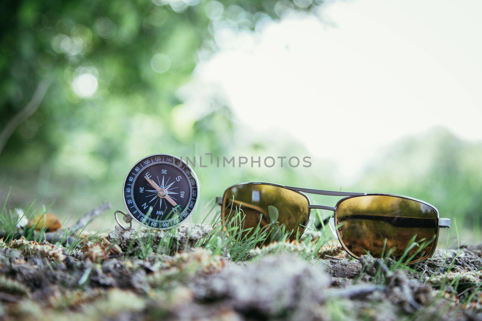 Vintage compass and sunglasses lying on the floor. Adventure and discovery concept.