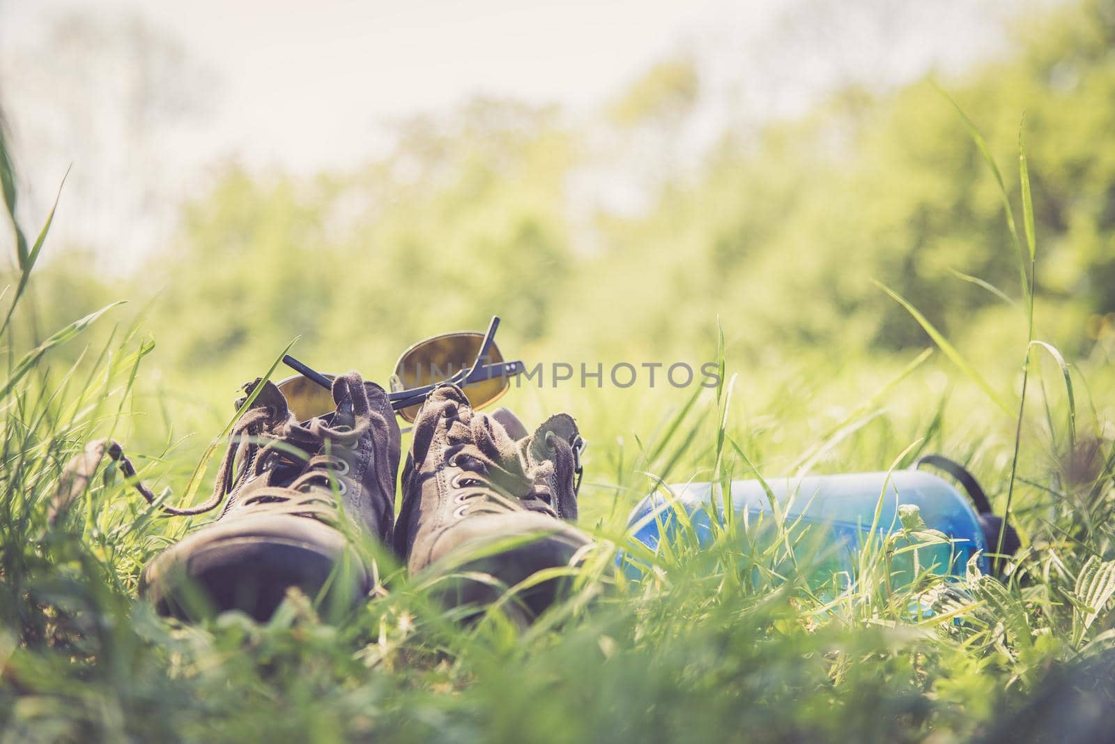 Shoes and a bottle of water in the green grass. Free time in summer.