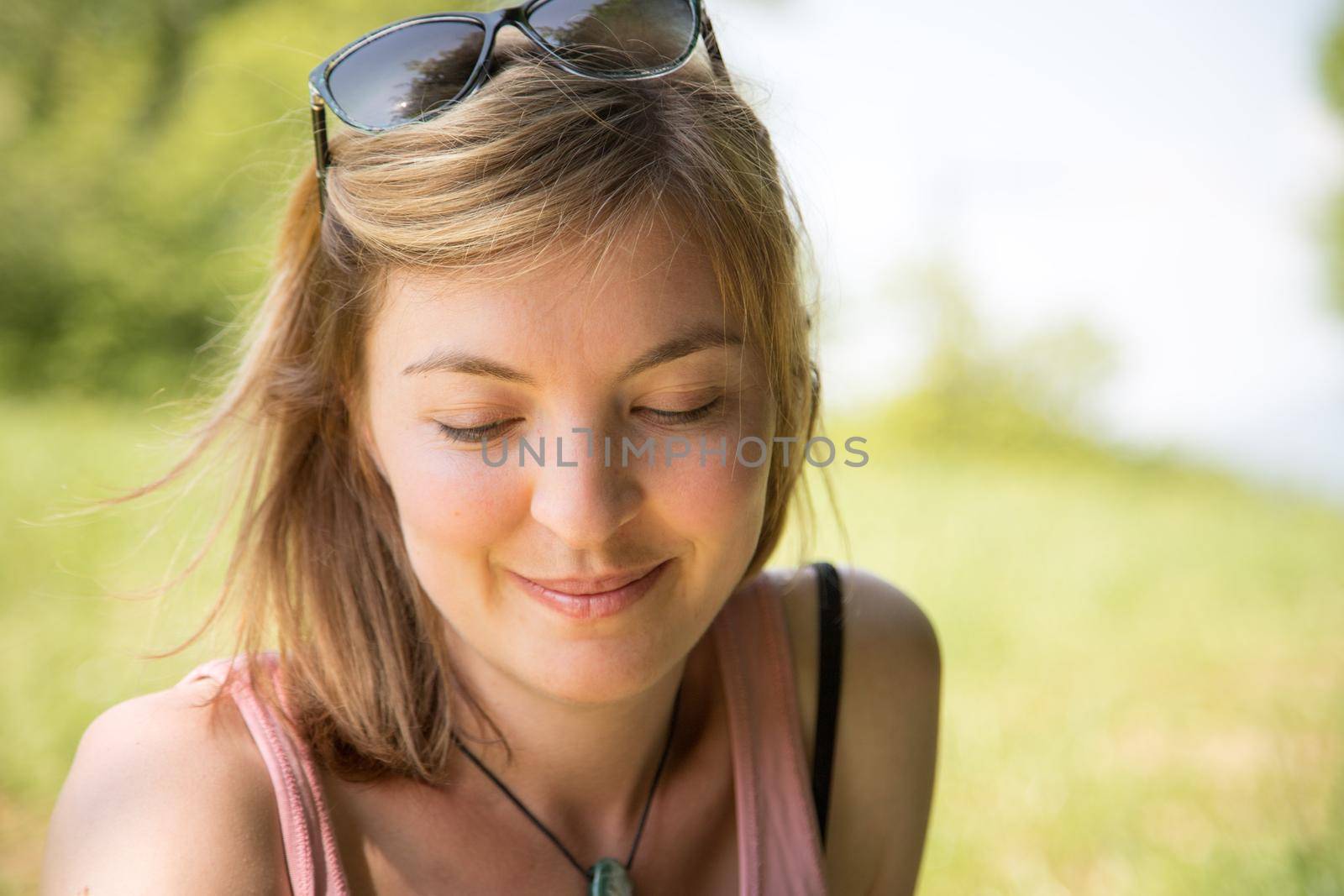 Portrait close up of young beautiful blonde woman outdoors in the park by Daxenbichler