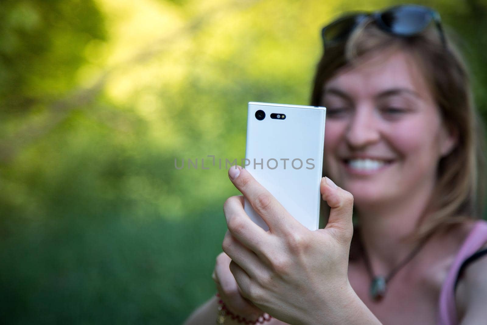 Girl is taking a picture with his mobile phone, outdoors in the park