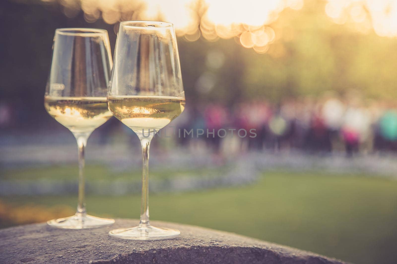 Glass of white wine on a stone wall in the formal garden. Enjoying it in the own garden in the evening sun.
