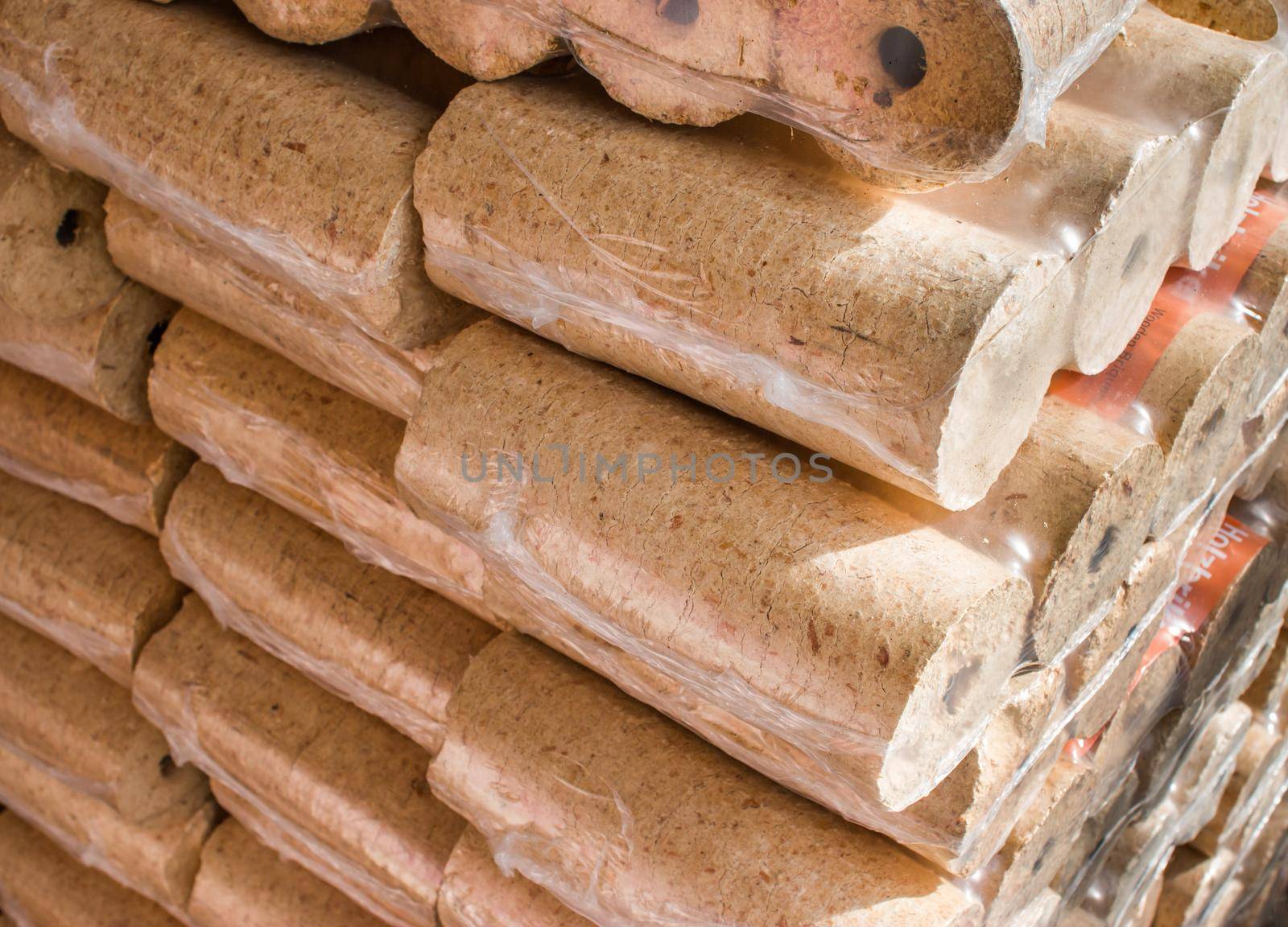 Fire briquettes for heating: Stacked firewood packed in plastic by Daxenbichler