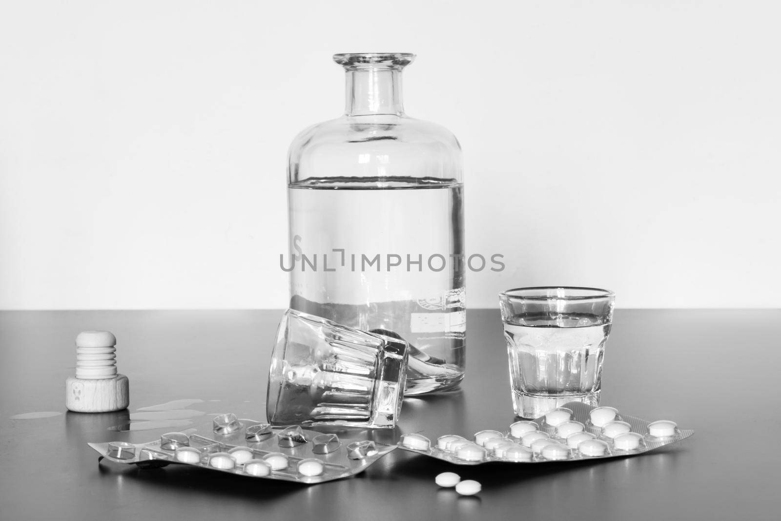 Pills and alcohol on a grey table. Concept for drug abuse.