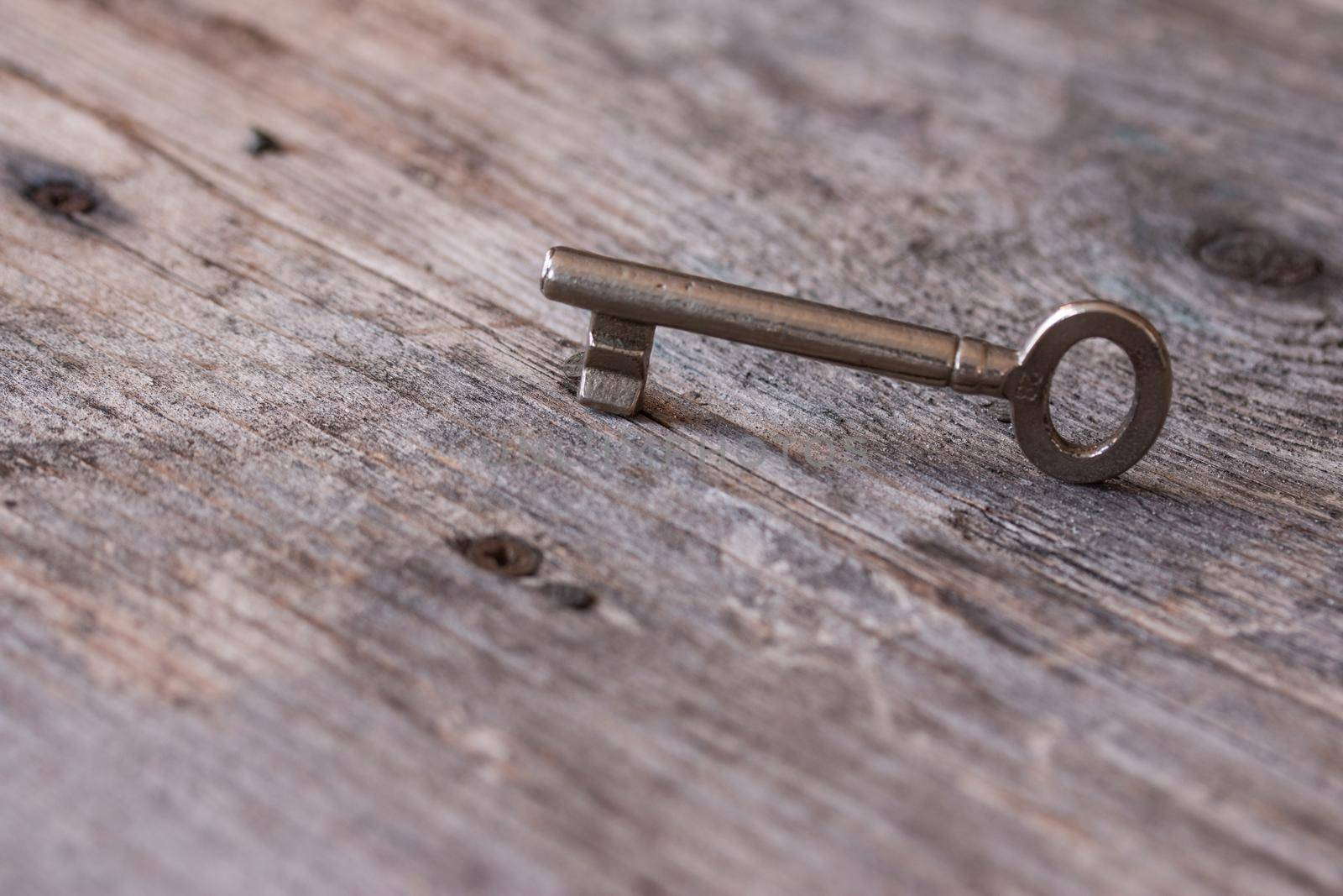 Old key is lying on a rustic wooden desk