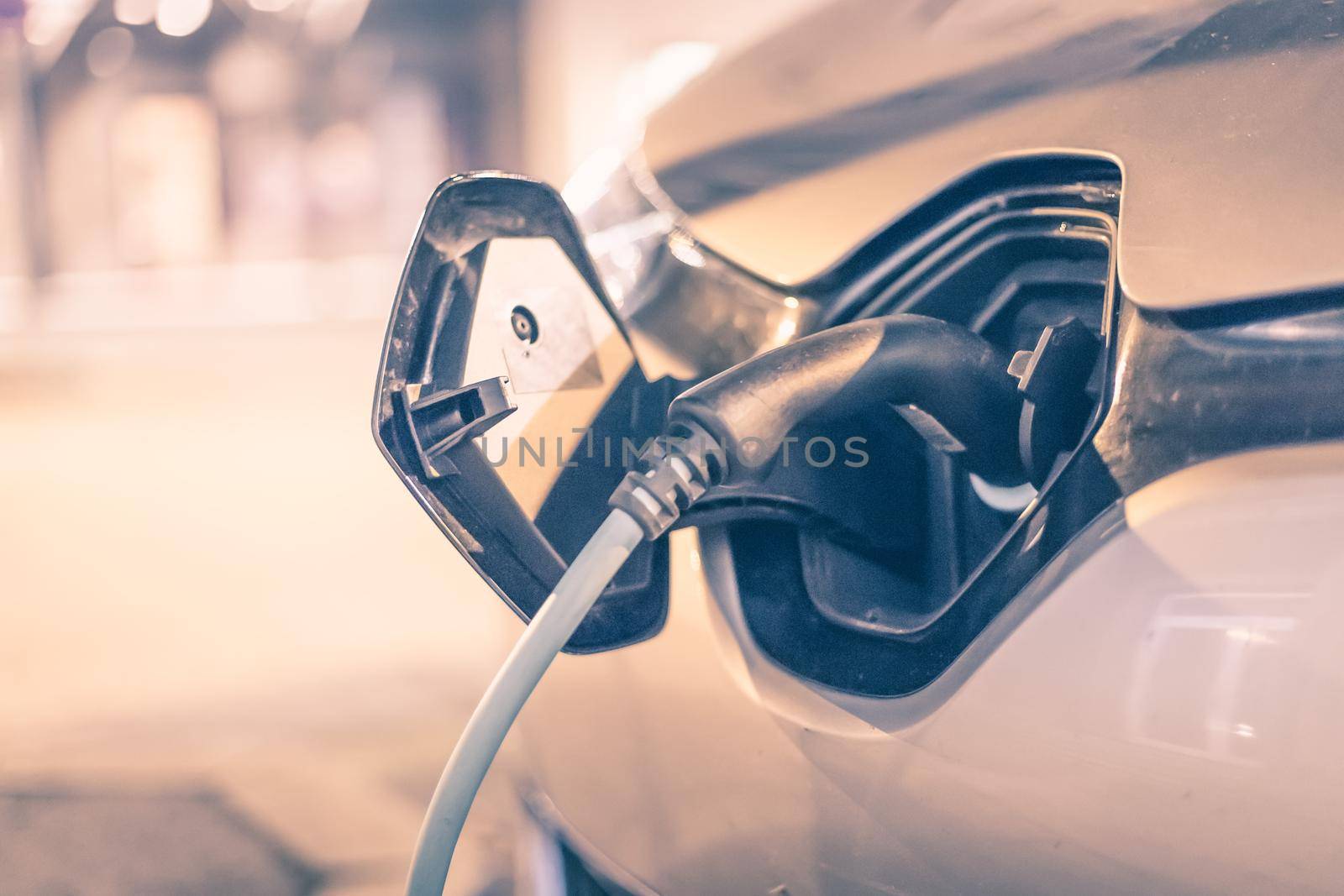 Electric car recharging with charge cable and plug leading to charge point.
