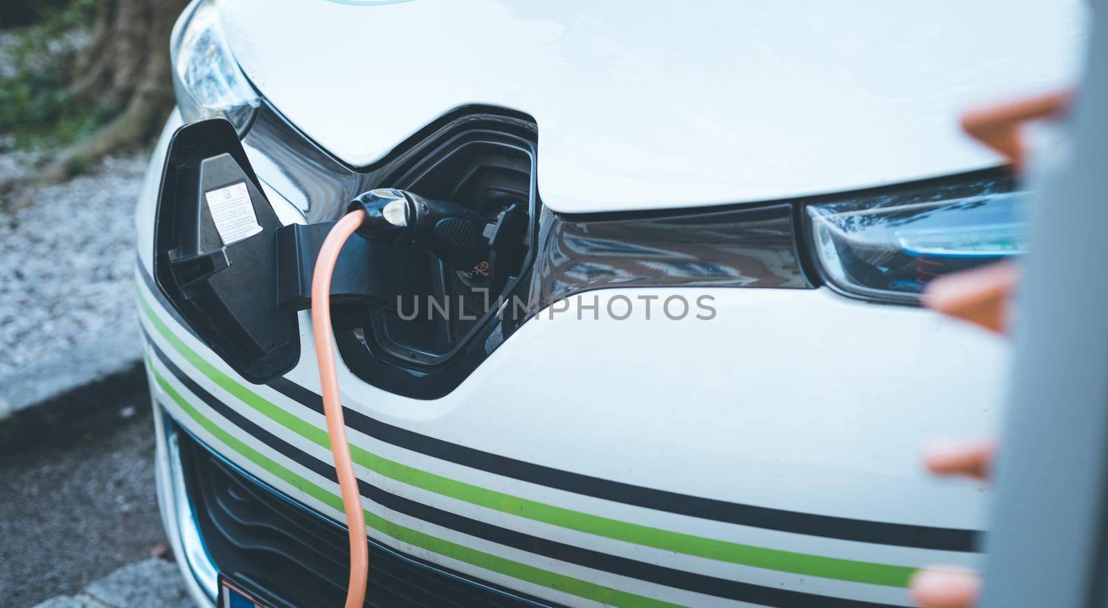 Electric car recharging with charge cable and plug leading to charge point.