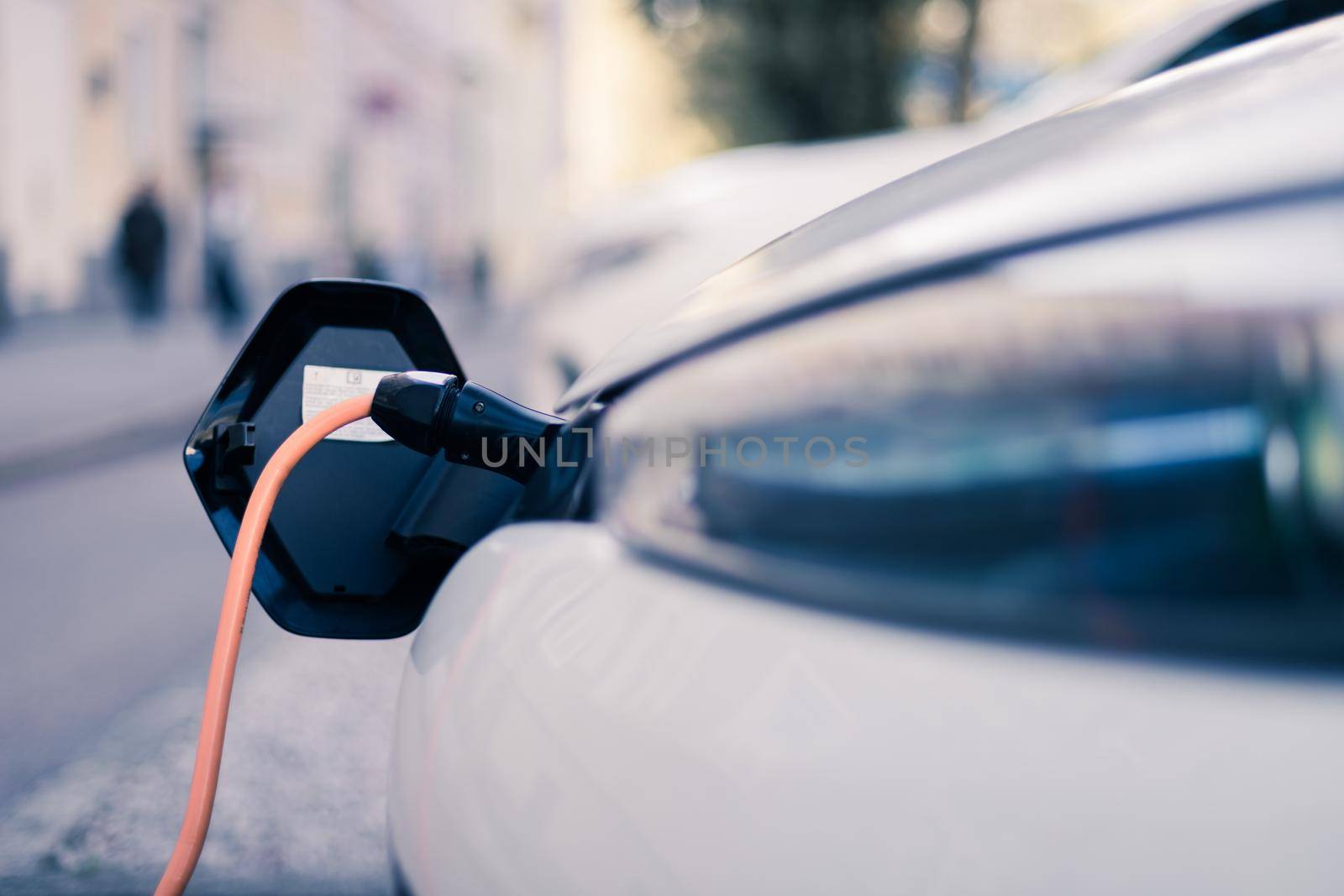 Electric car recharging with charge cable and plug leading to charge point.