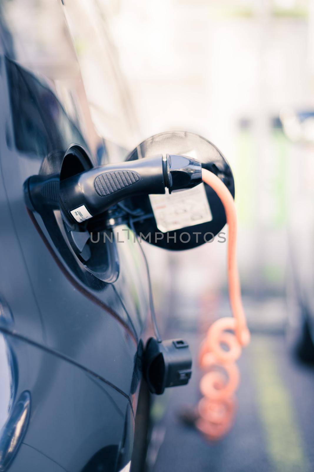 Charching an electric car with power cable supply, plugged in by Daxenbichler