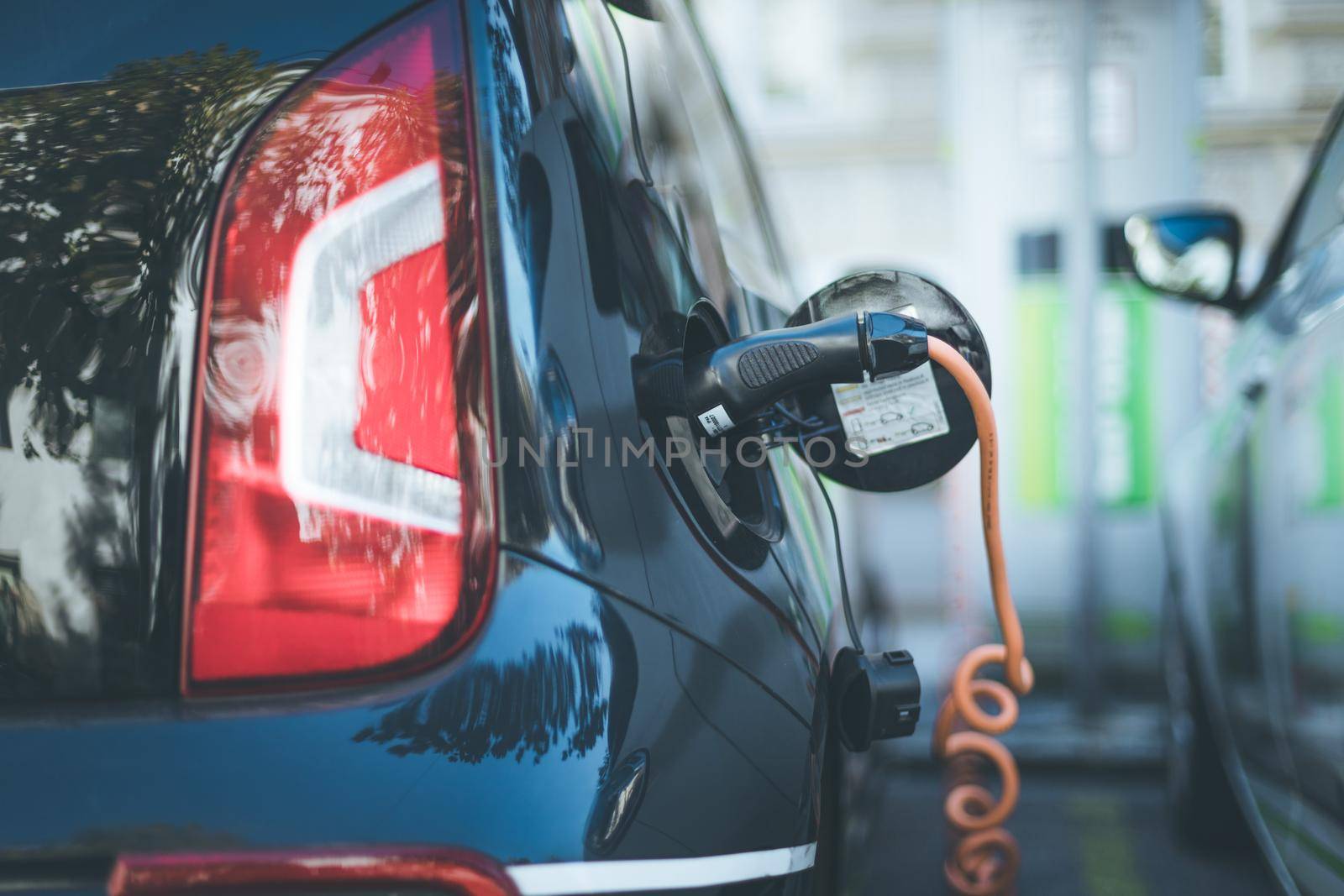 Electric car recharging with charge cable and plug leading to charge point.