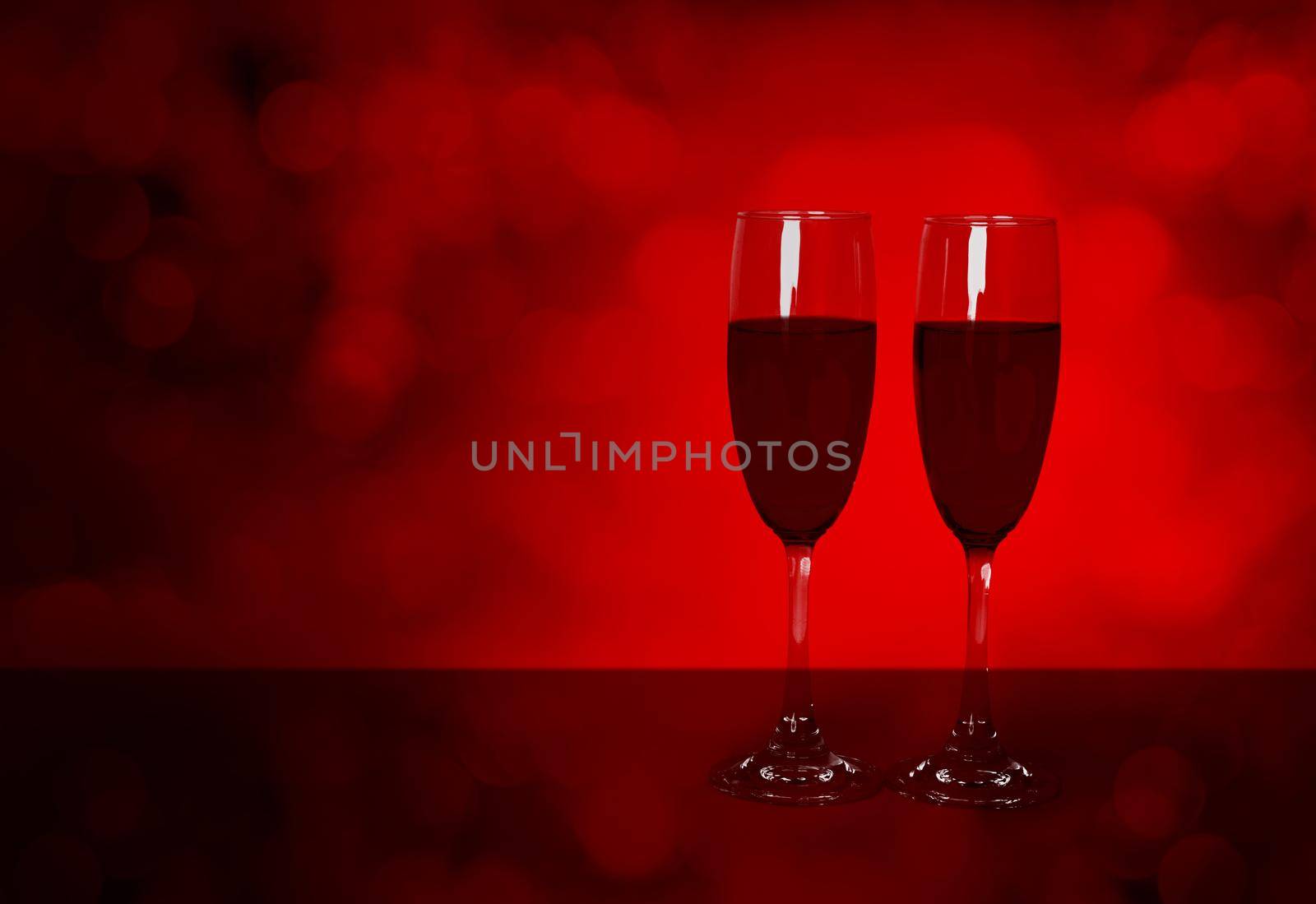 Two wineglasses on desk with red blur bokeh background, champagne glasses with celebration and anniversary with luxury, love and romantic, red wine, copy space, valentine day and holiday concept.