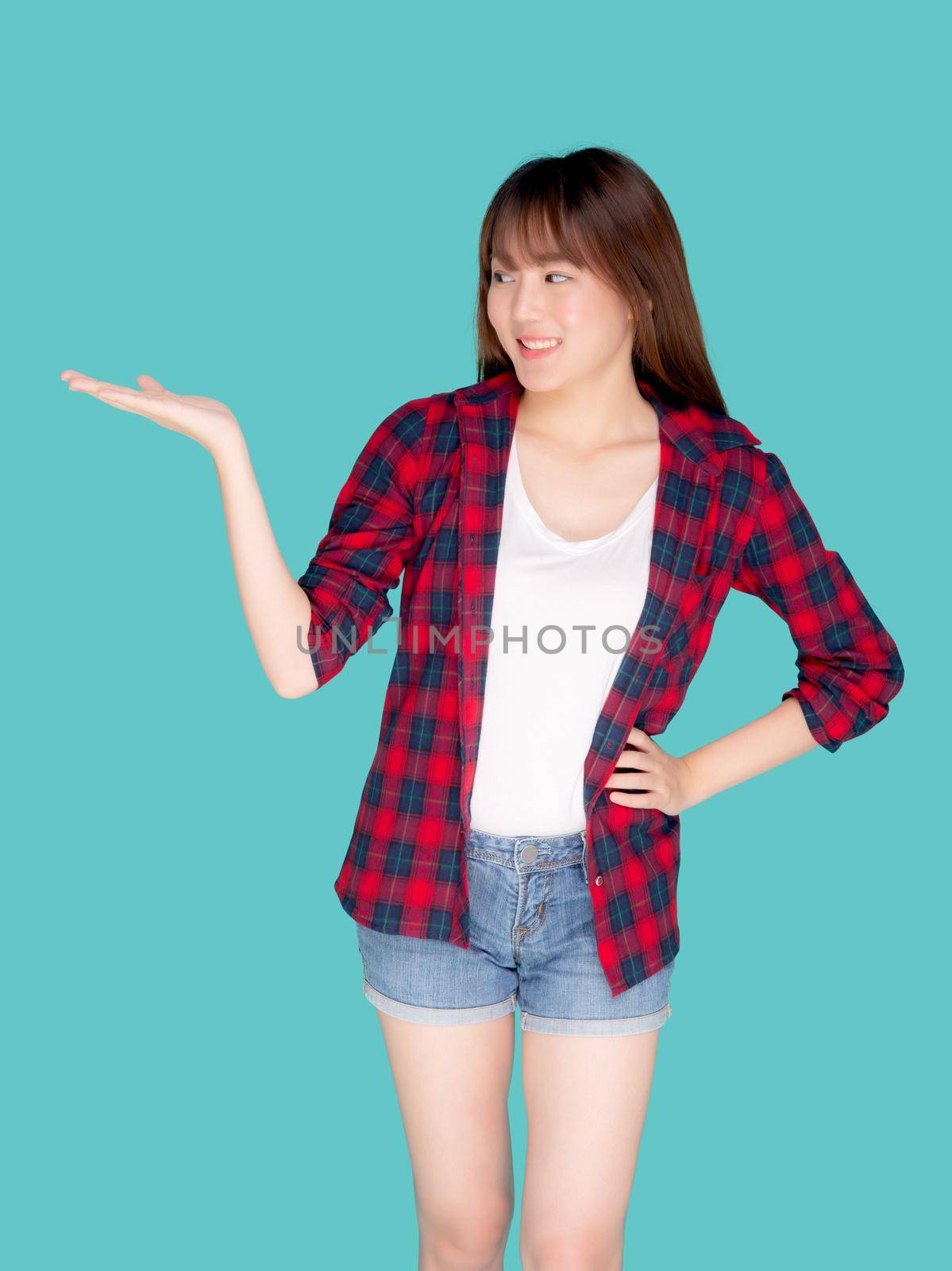 Beautiful portrait young asian woman smiling gesture presenting something and excited summer holiday isolated blue background, asia girl confident and cheerful with journey, travel concept.
