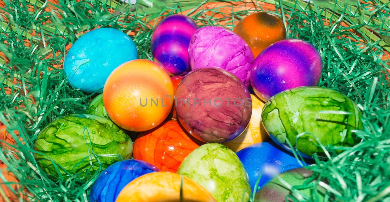 Colorful eggs in the basket on green grass Background