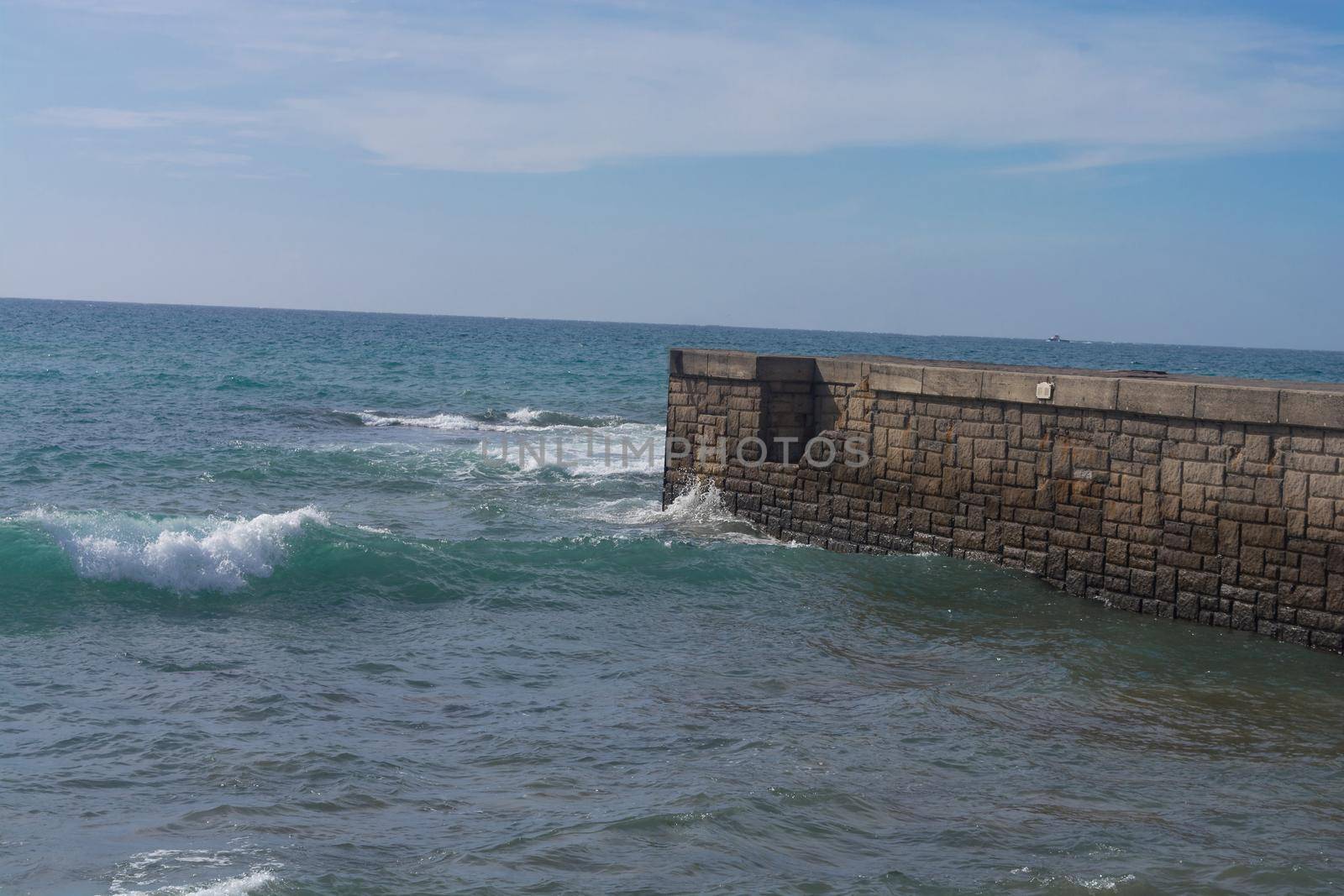 High waves at a breakwater on Cran Canaria in Meloneras, beach near lighthouse.