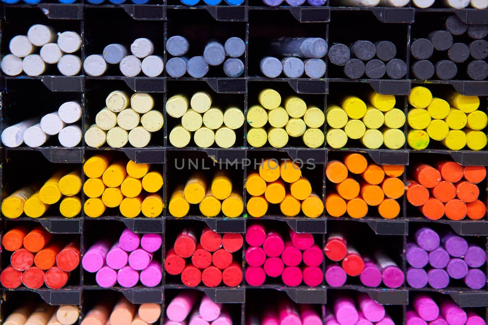 Multicolored pastel crayons art store in wooden cells. Artspace, workshop, creativity concept. Modern art. Style abstract background