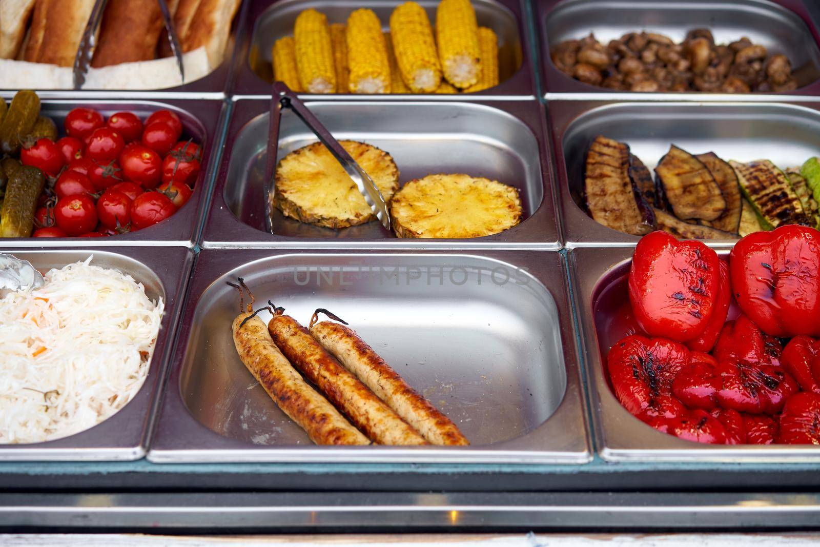 Street food grilled tomato, sausages, pineapple, sauerkraut, pepper, vegetable, corn, showcase market in metal plate