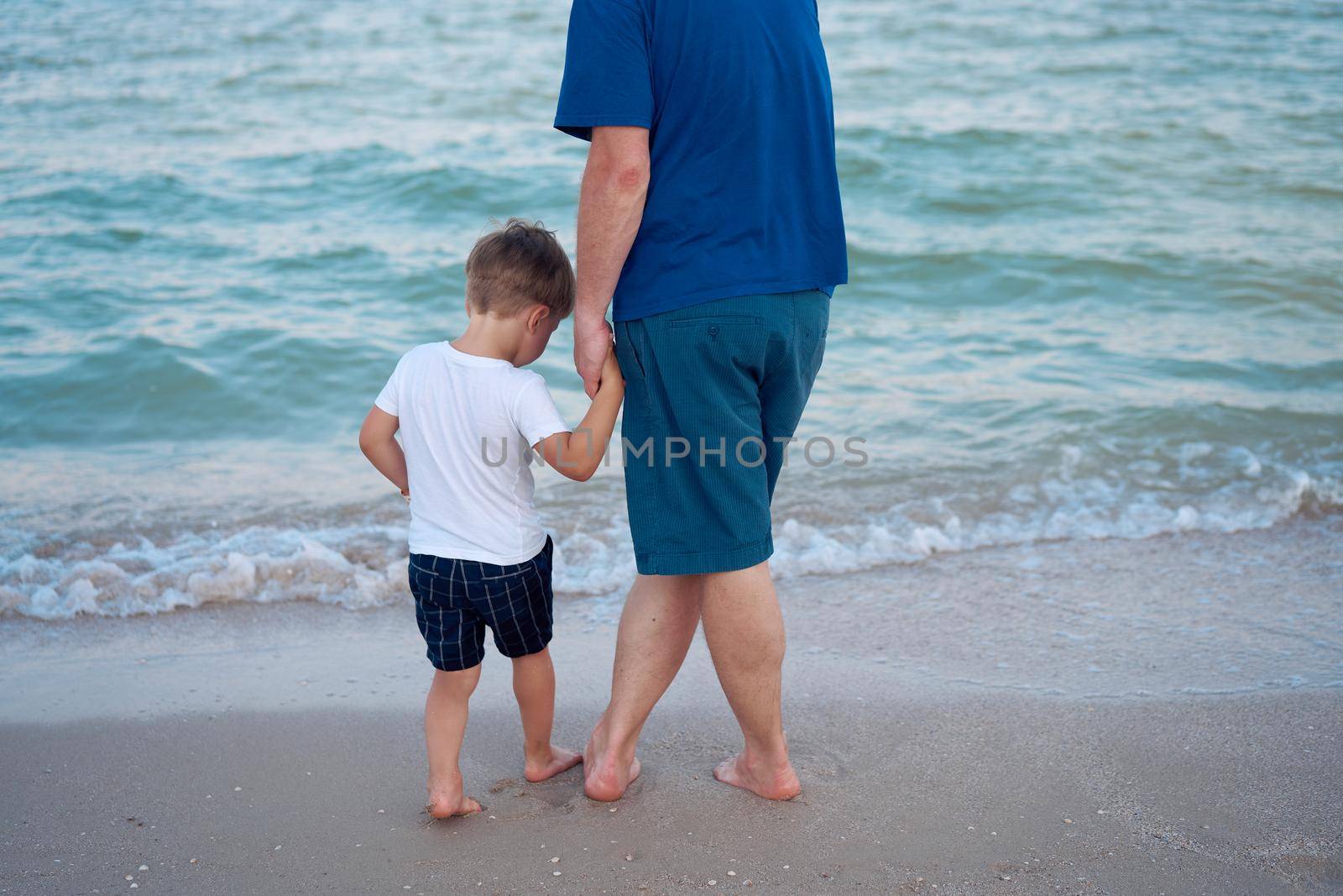 Dad holds son hand. Father Child spending time together sea vacation Young man little boy walking beach Fathers day. Family with one child. Happy childhood with daddy.