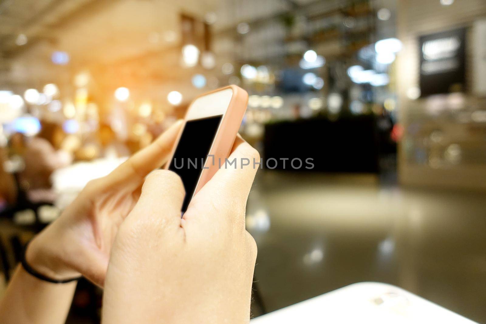 Close up of women's hands with a pink nails holding cell telephone, hipster girl watching video and texting a message to her family on mobile phone during coffee break in restaurants by NarinNonthamand