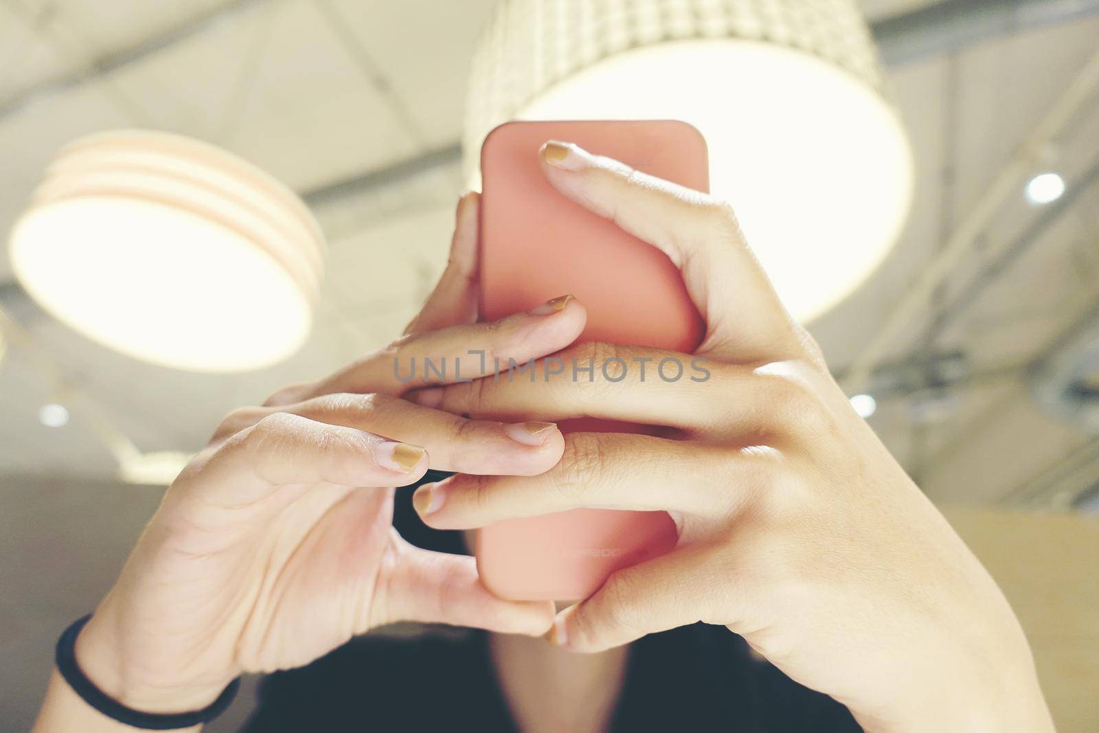 Close up of women's hands with a pink nails holding cell telephone, hipster girl watching video and texting a message to her family on mobile phone during coffee break in restaurants by NarinNonthamand