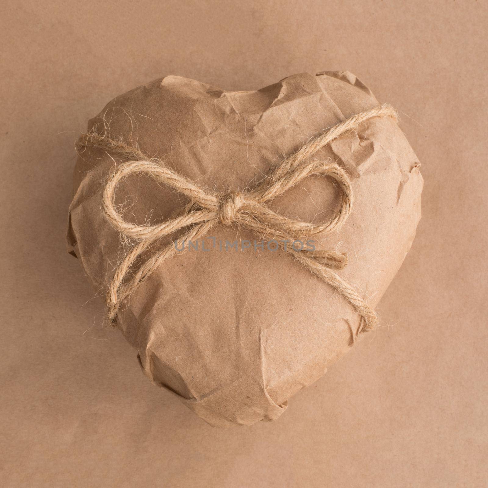 Heart gift in brown Wrapping craft Paper tied with rope bow on background Valentine day surprise concept