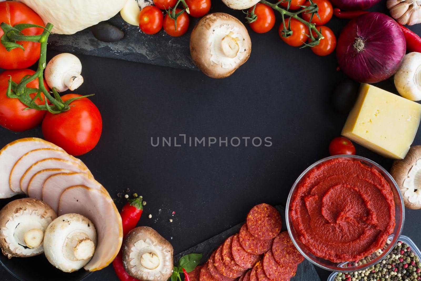 Raw dough for pizza with ingredients and spices on black table background in heart shape love food of Valentines day concept