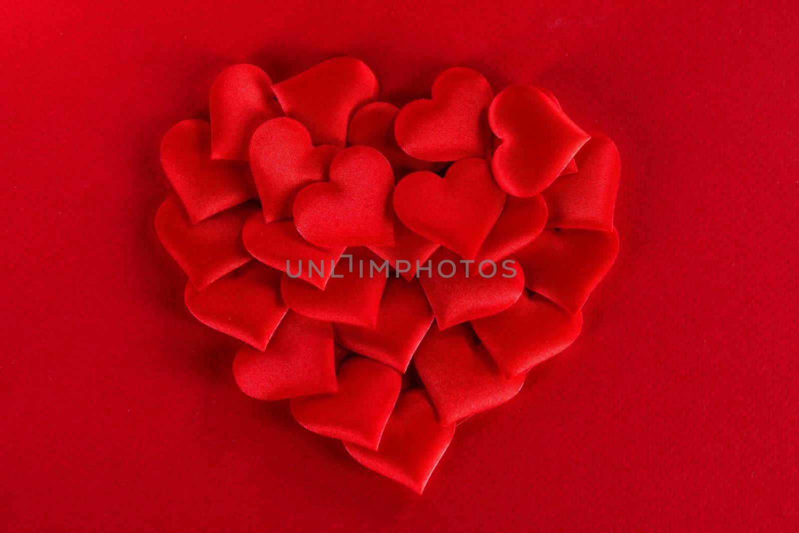 Valentine's day many red silk hearts on red background, love concept