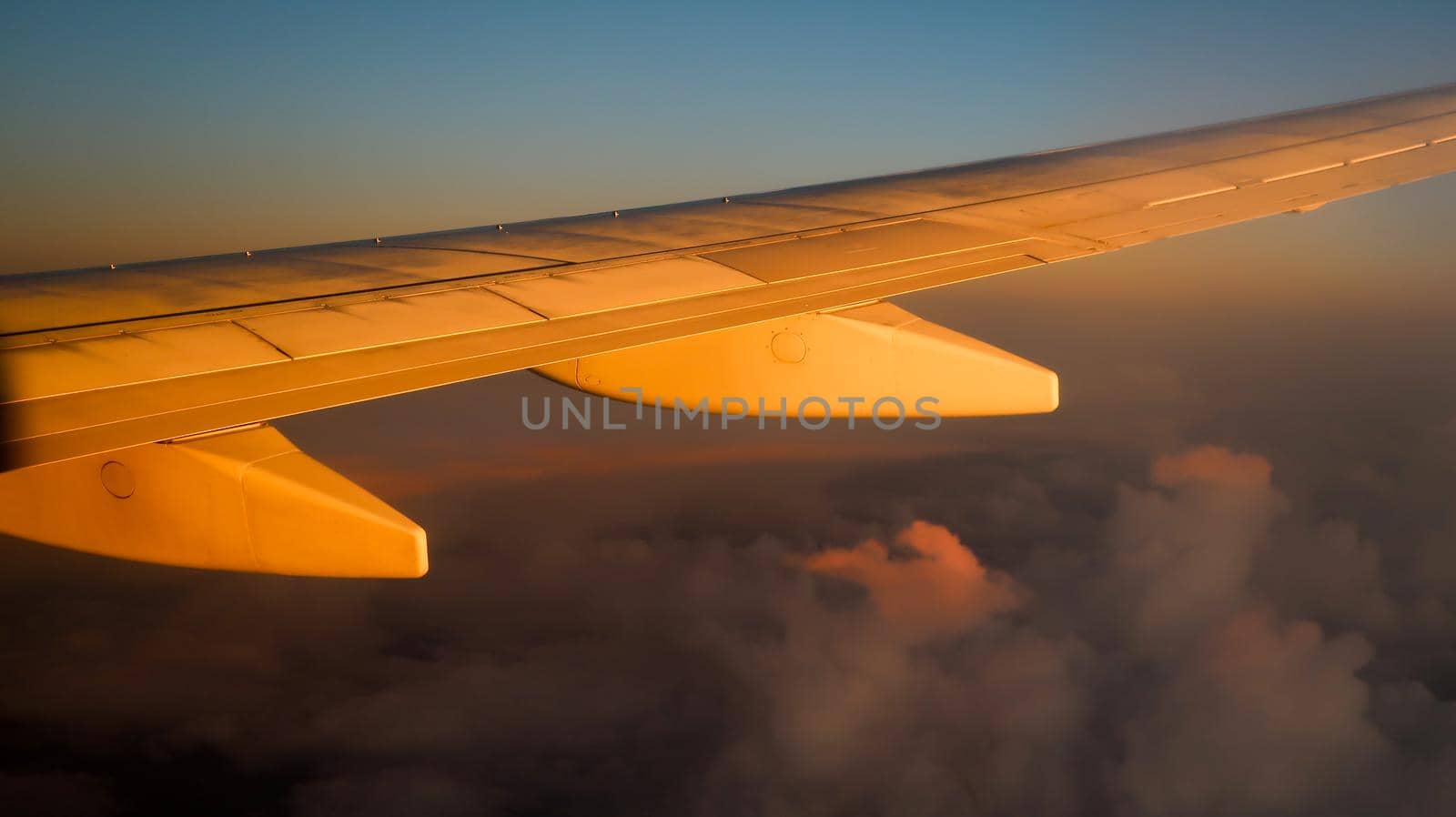 Airplane wing during sunset with cloudscape