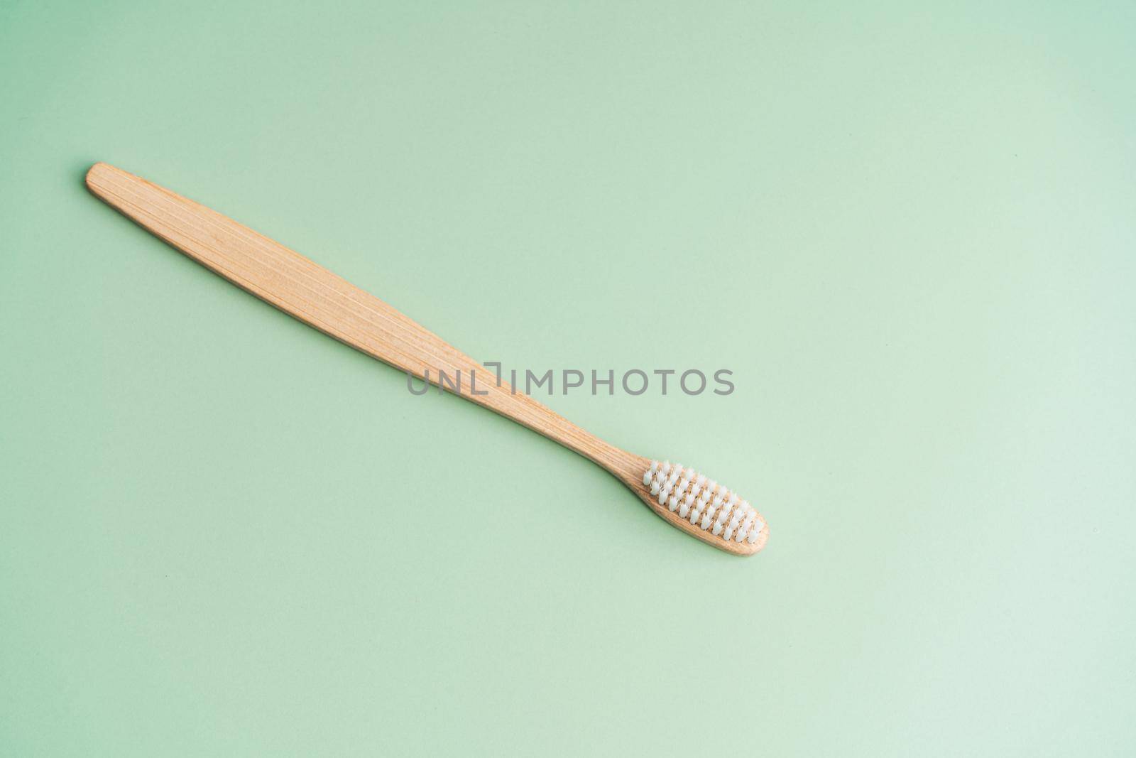 Eco friendly dental health antibacterial bamboo wood toothbrush on green background.