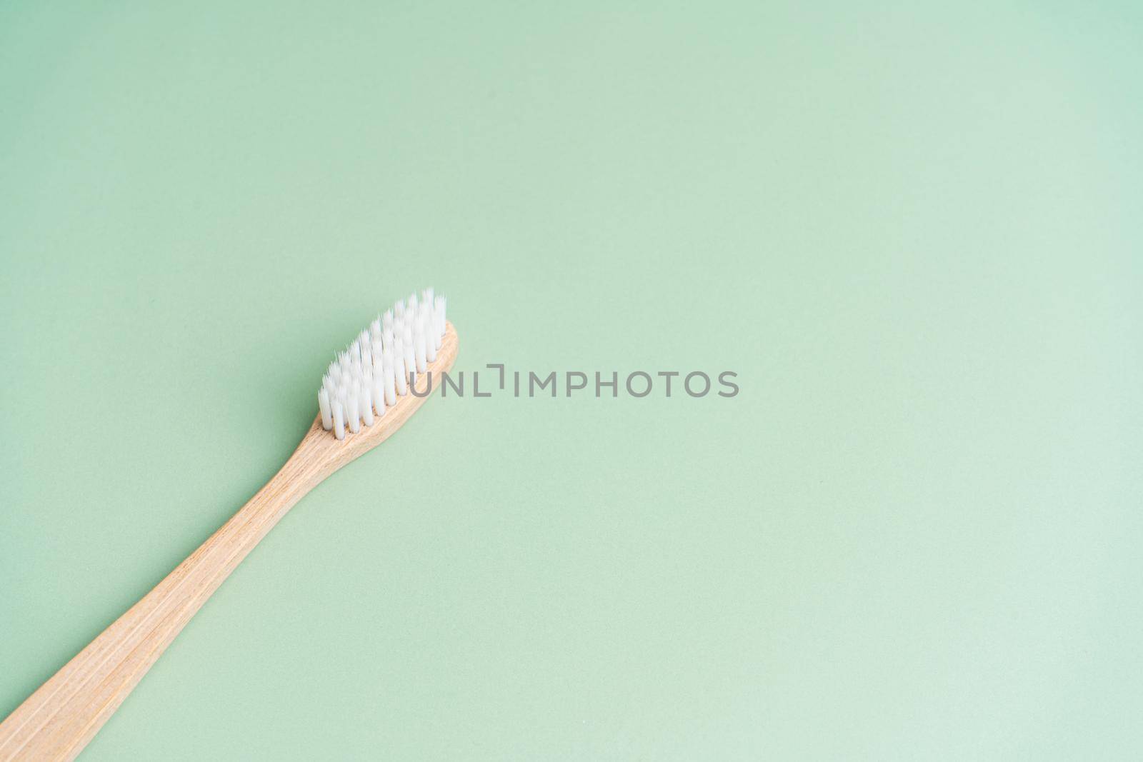 Eco friendly dental health antibacterial bamboo wood toothbrush on green background by Try_my_best